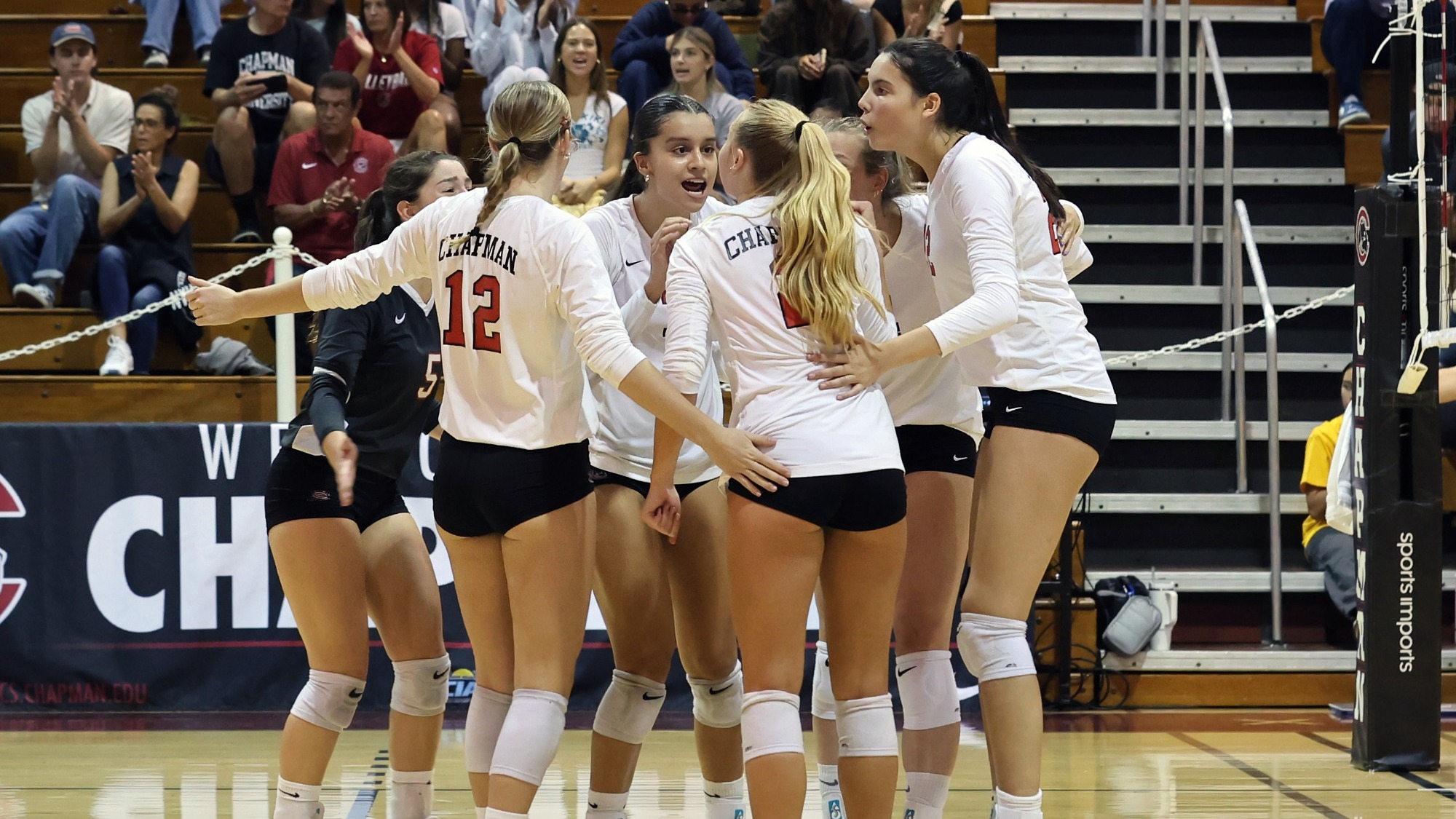 A group of volleyball players huddle on the court.