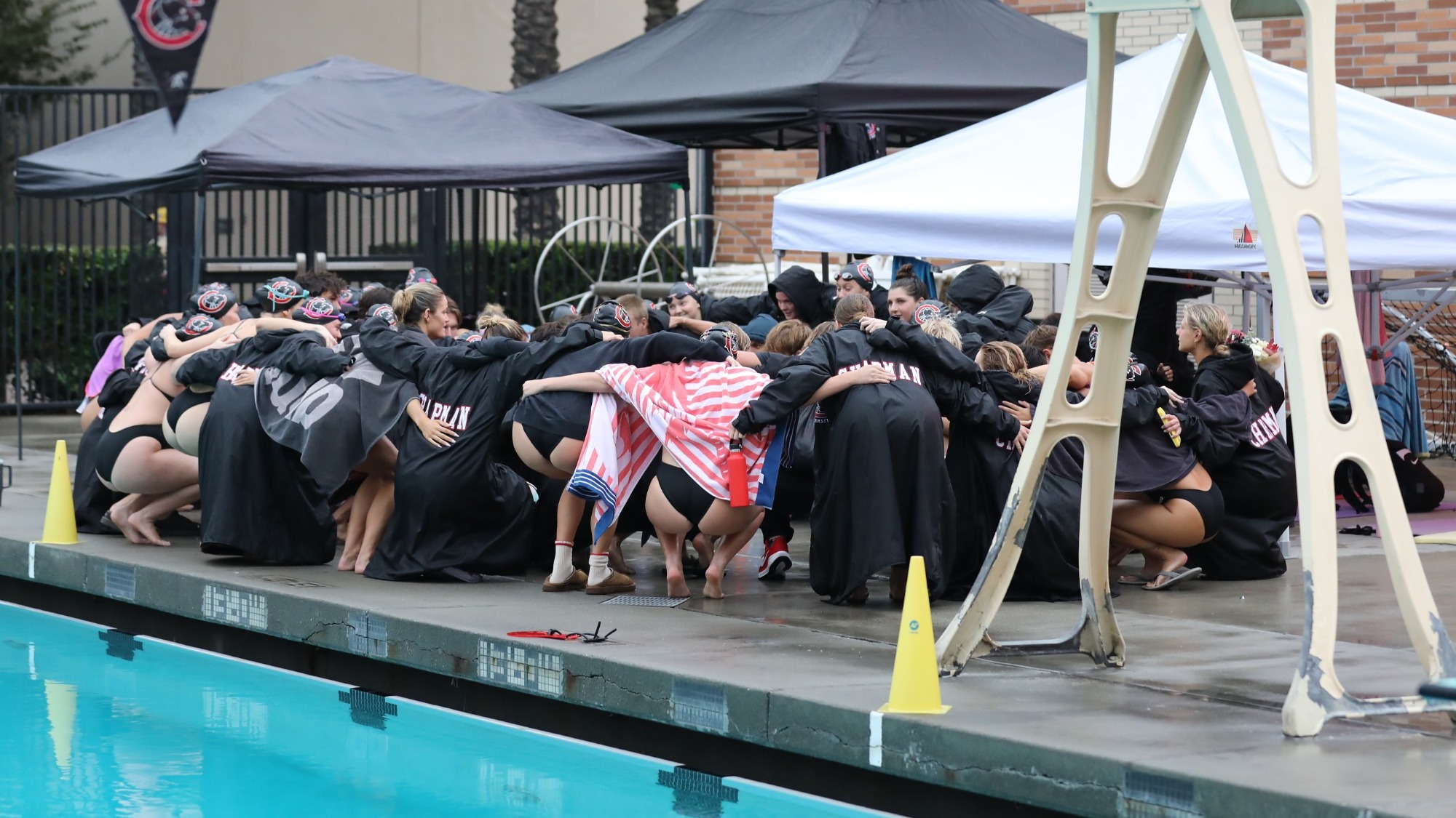 The swim team cheers on the pool deck before the meet. 