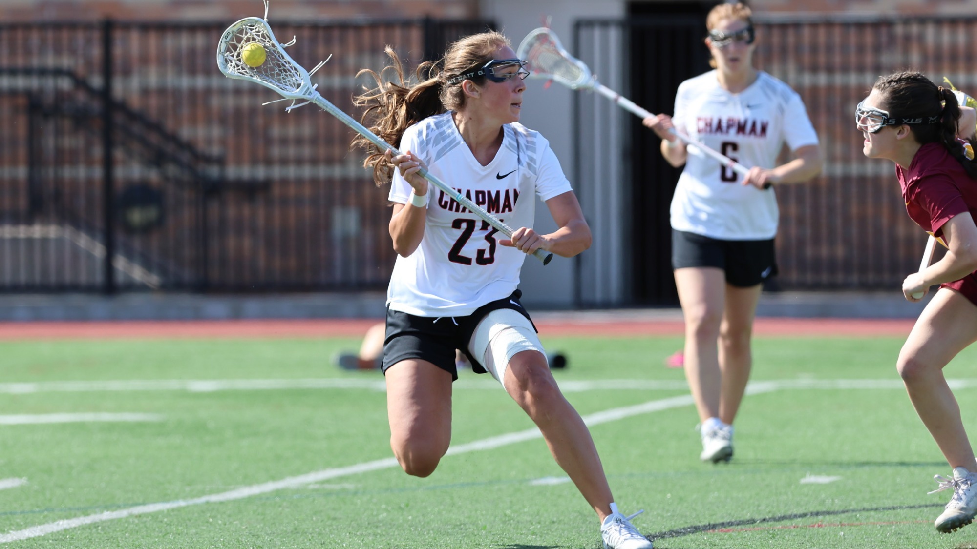 Zoey Stephens playing lacrosse on the field against a defender.