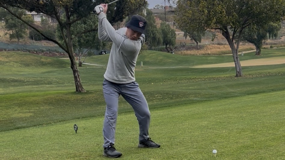 Kendrick Tan hits a golf ball off the tee.