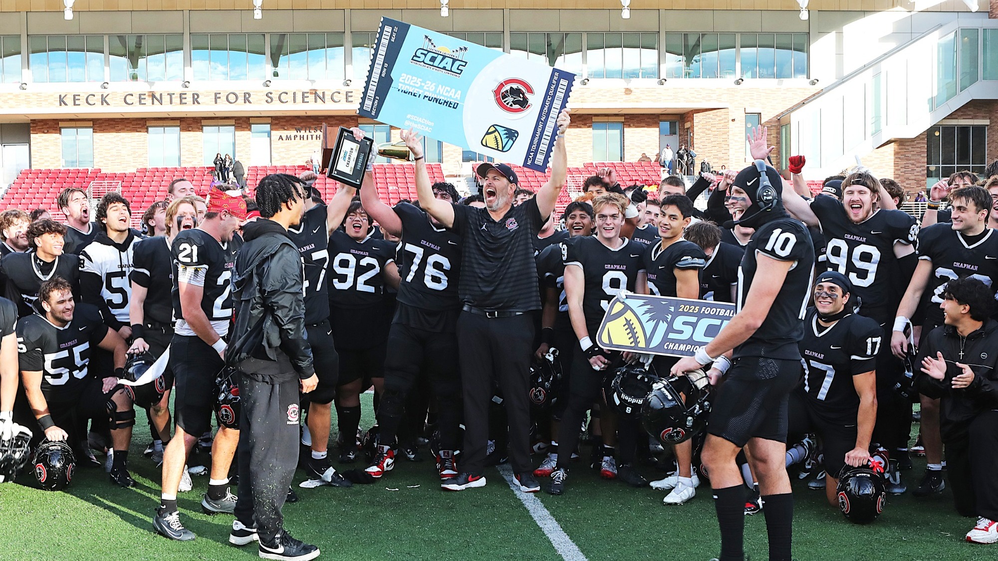 Casey Shine holds up a sign in celebration with the team after winning a championship.