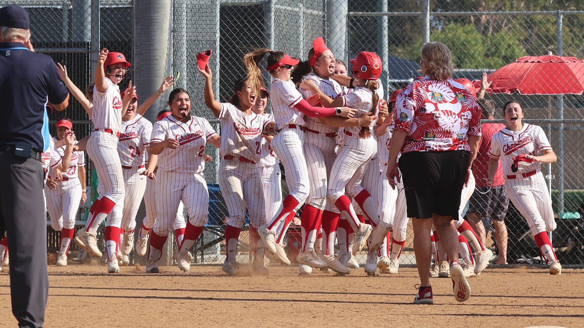 The softball team jumps on the field in celebration of a game-winning hit.