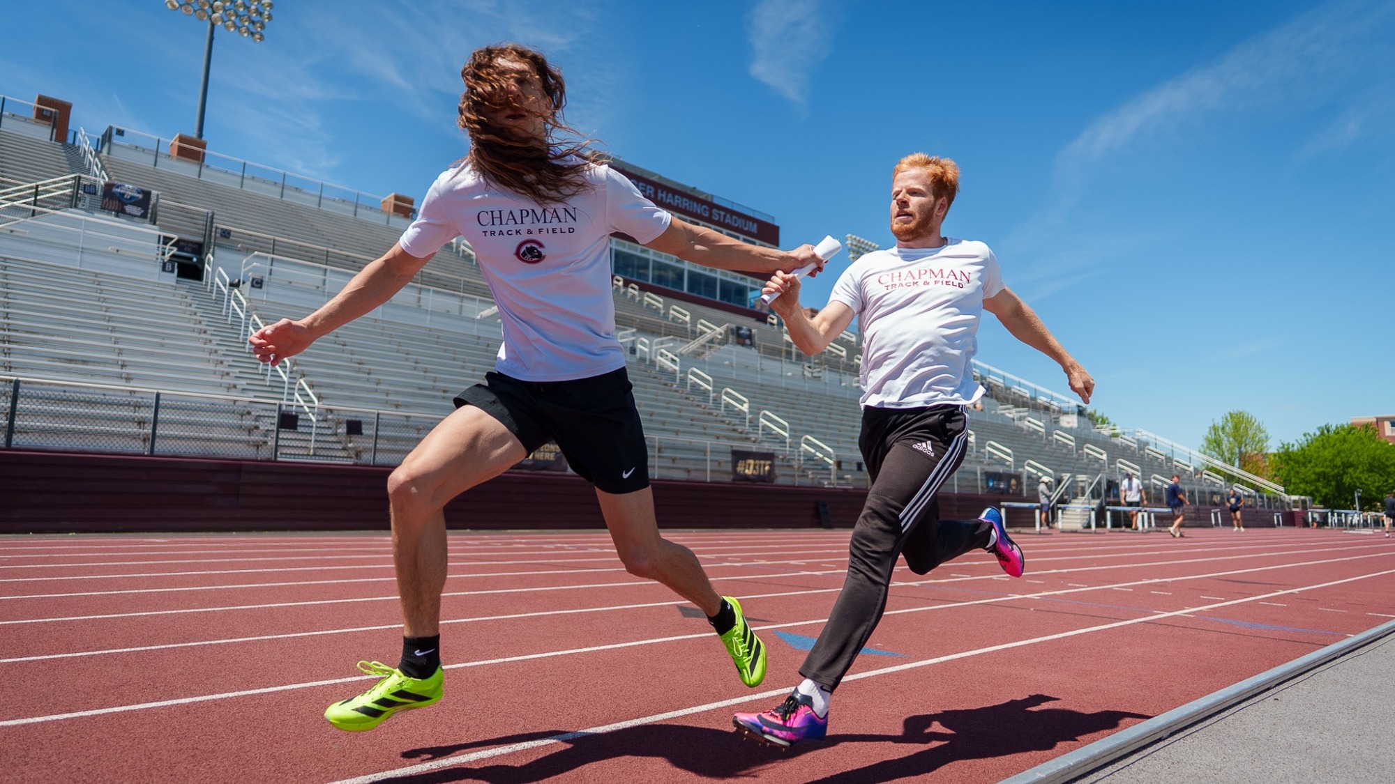 Mason Fara hands Wyn Smoole the baton during a track relay race.
