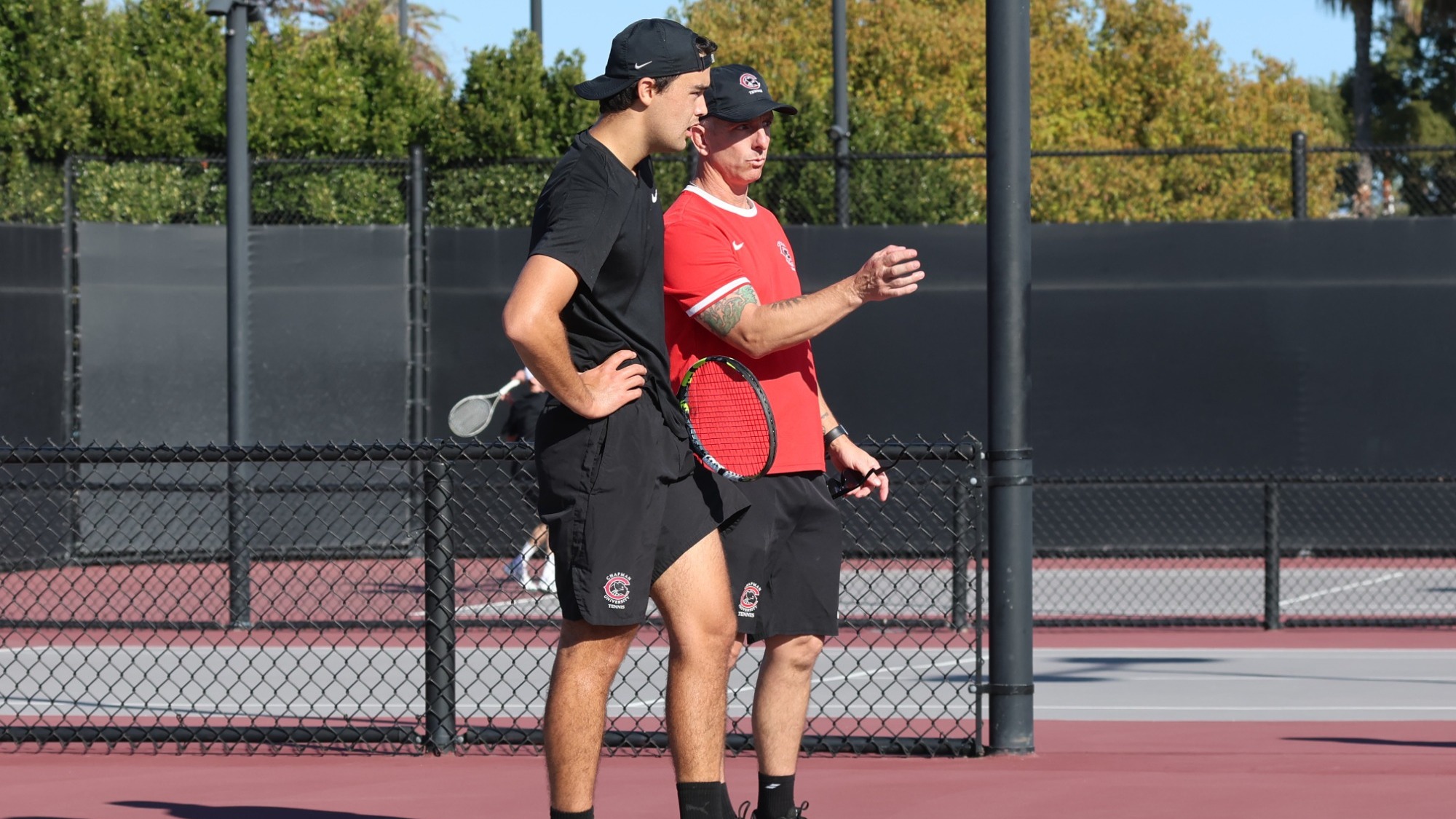 Evan Parry talking with Ben Jorgenson between  points on the tennis court.