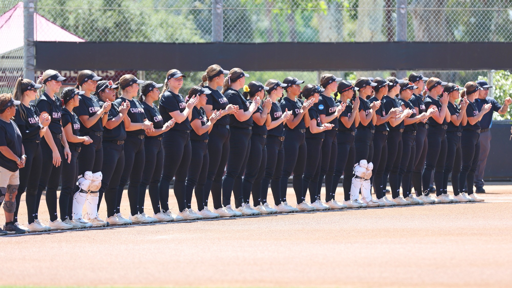 Softball players lined up along the foul line.