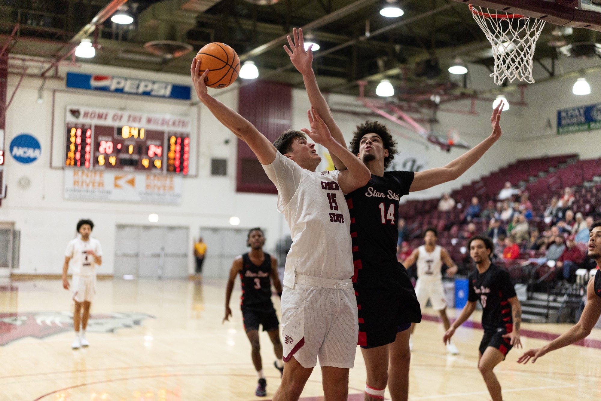 Braddock Kjellesvig going up towards the basket as a Stanislaus State defender tries to block the attempt