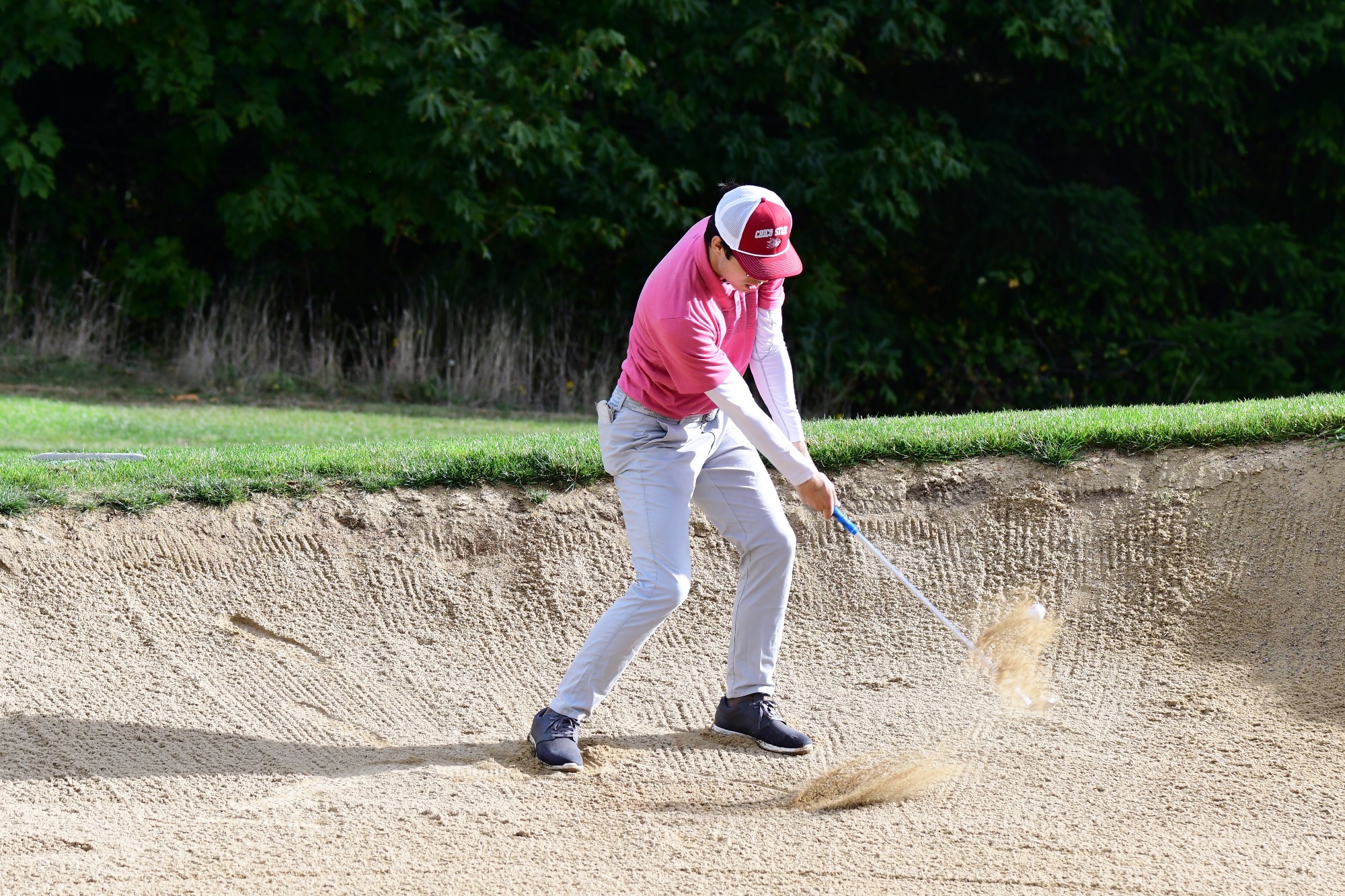 Naoki Easterday hitting the ball out of a bunker at the Bishop invite