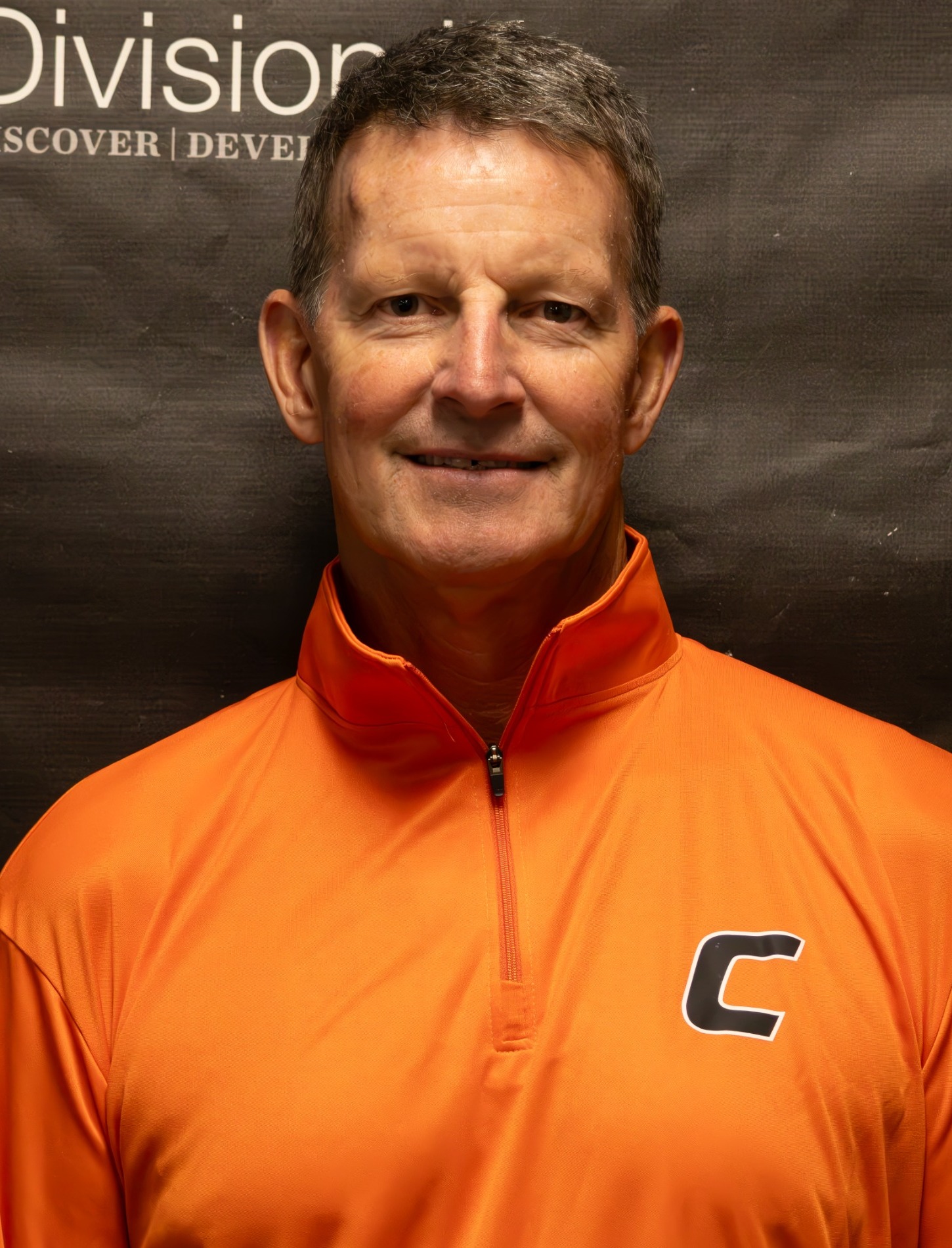 Paul Fowler headshot wearing orange zip-up