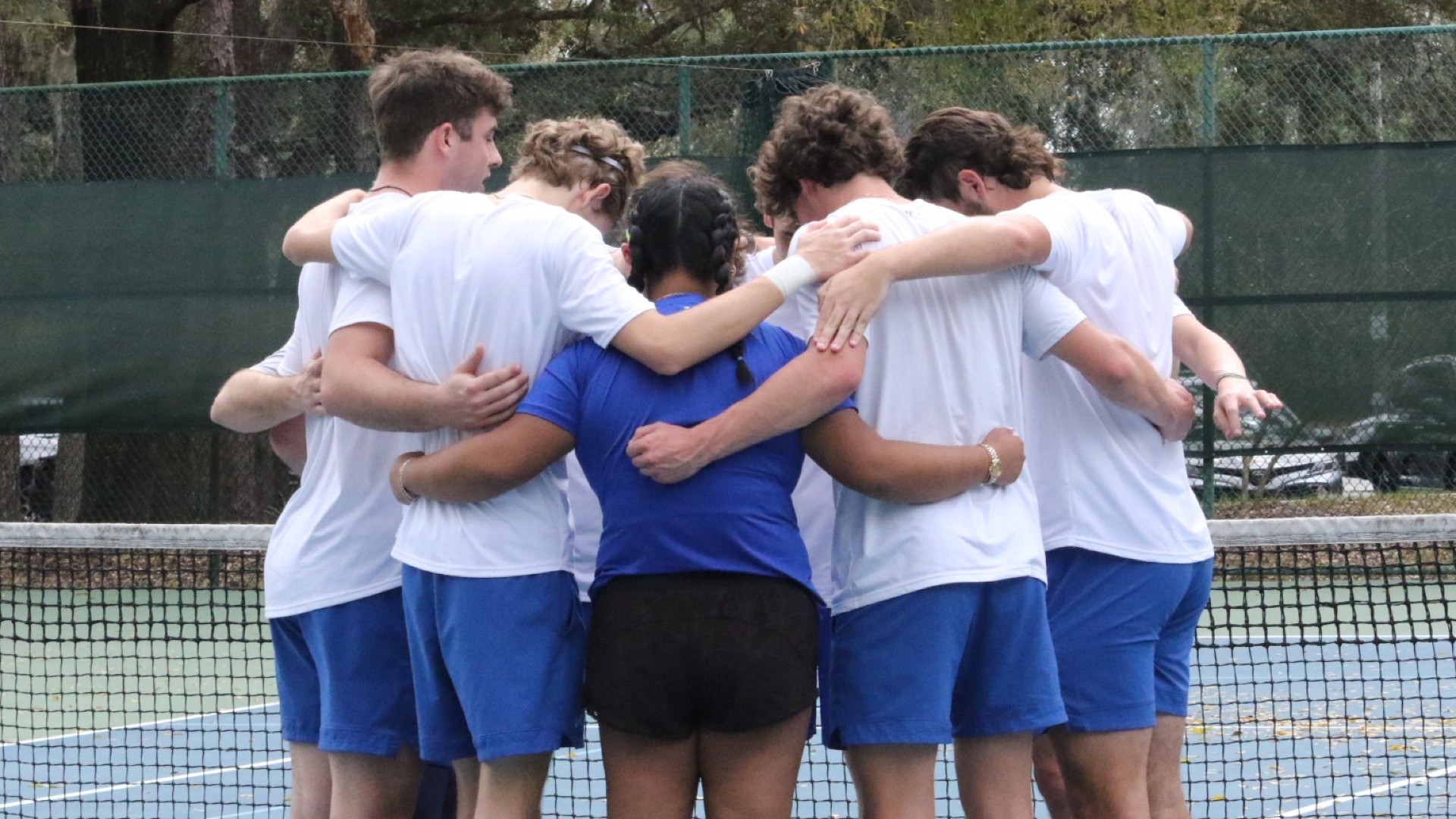 The CUW men's tennis team huddled together.