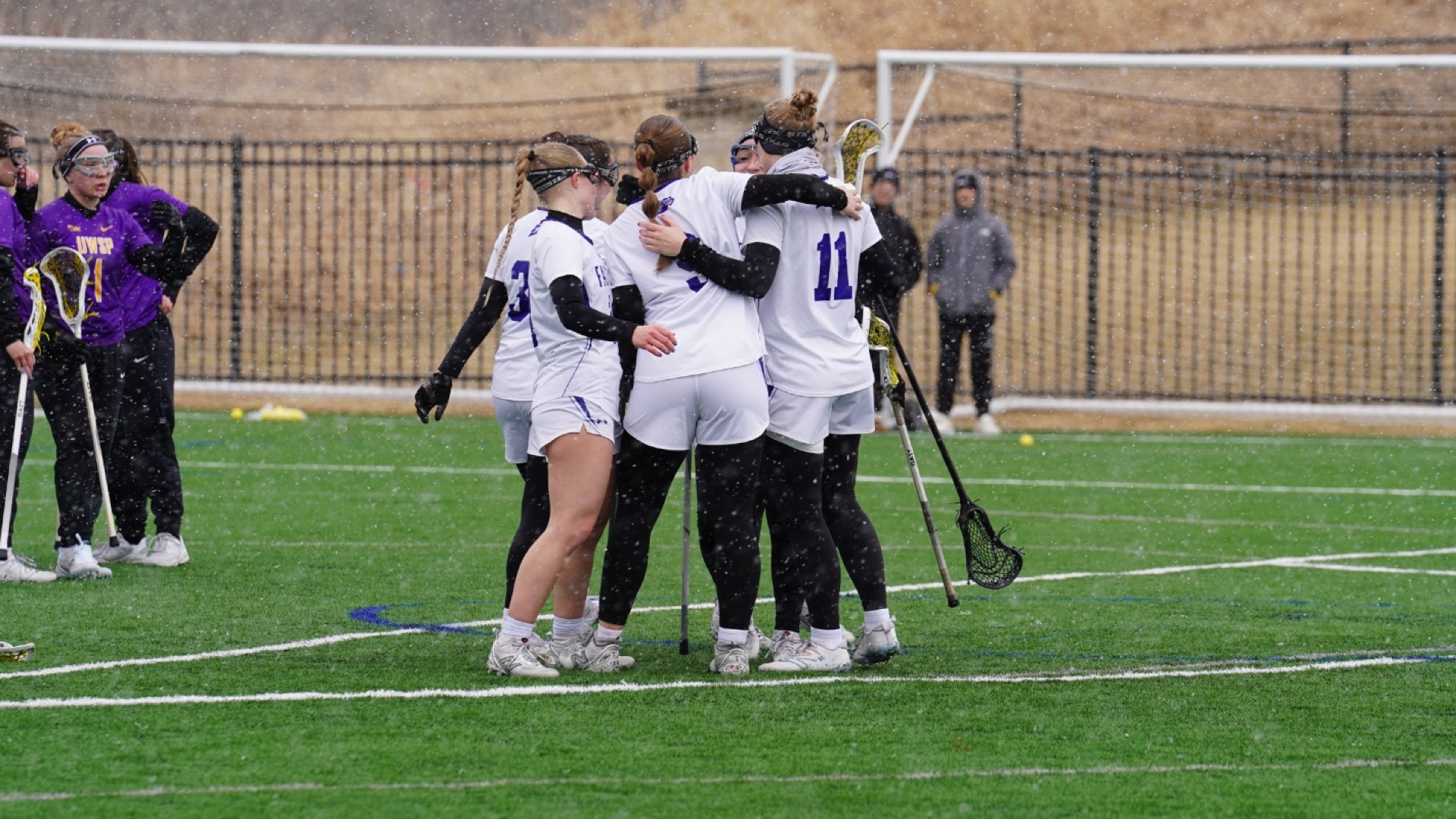 the CUW women's lacrosse team huddle together after the goal. 