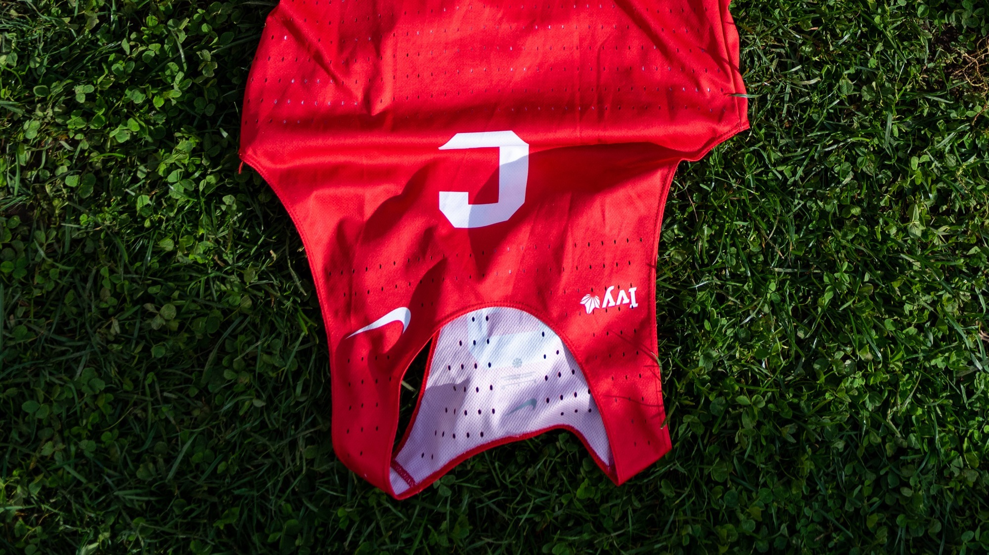 Cornell cross country tank top laying on the turf field of Cortlandt Park at the Heptagonal Championships.