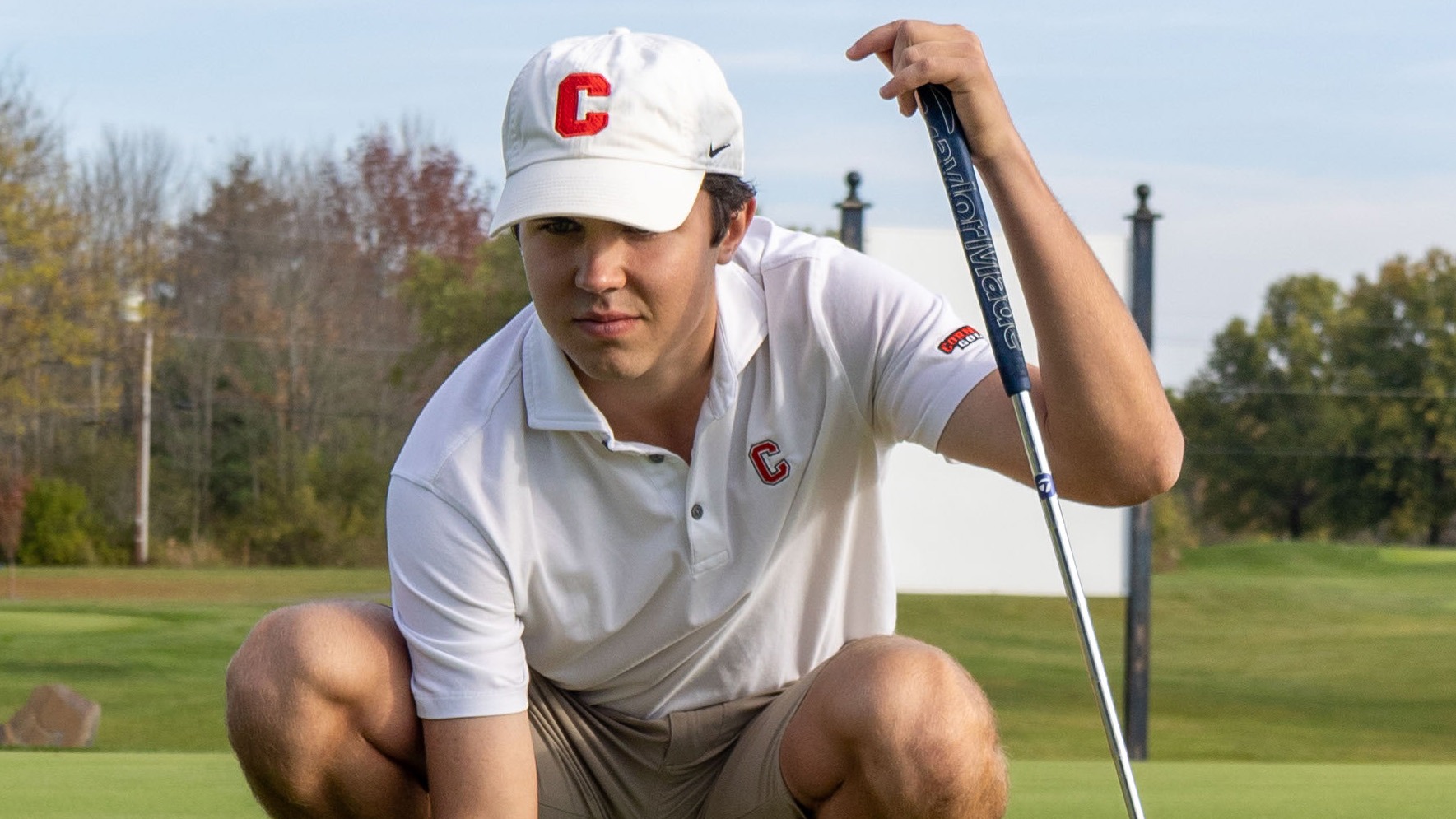 Tyler Debusschere crouches down to line up his golf ball during media day for the 2023-24 Cornell men's golf team.