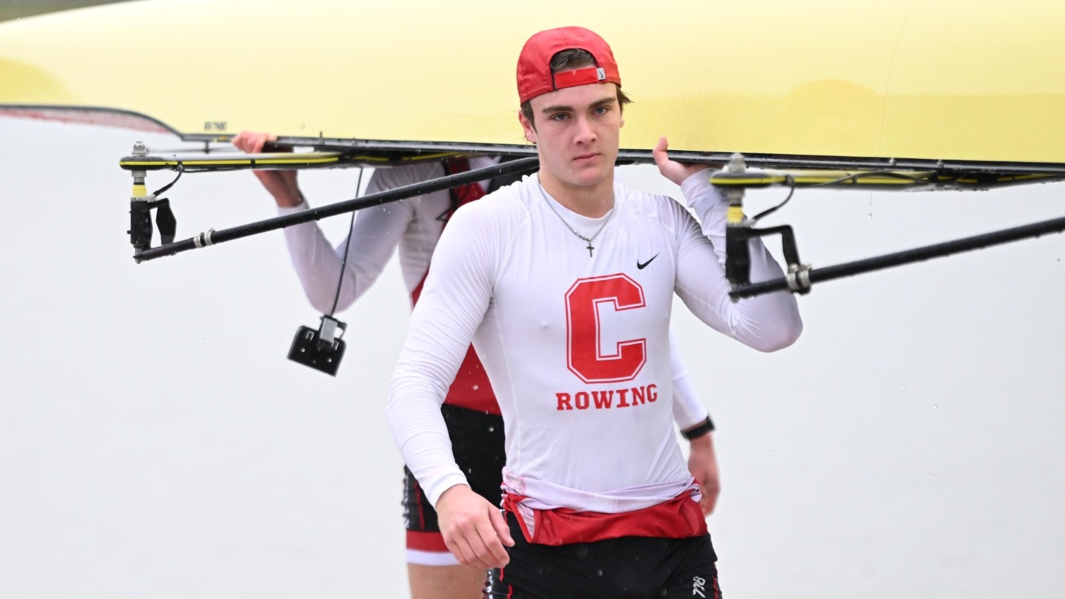 Cornell men's heavyweight rower Xavier Wendt carries a boat into the Cornell Rowing Center after race action against Harvard on April 5, 2025, on the Cayuga Inlet in Ithaca, N.Y.
