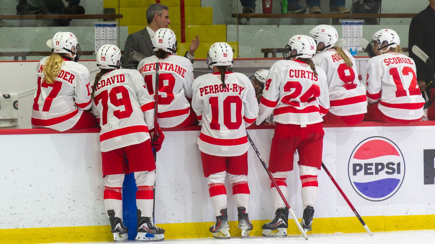Womens hockey huddles on the bench at Lynah Rink.