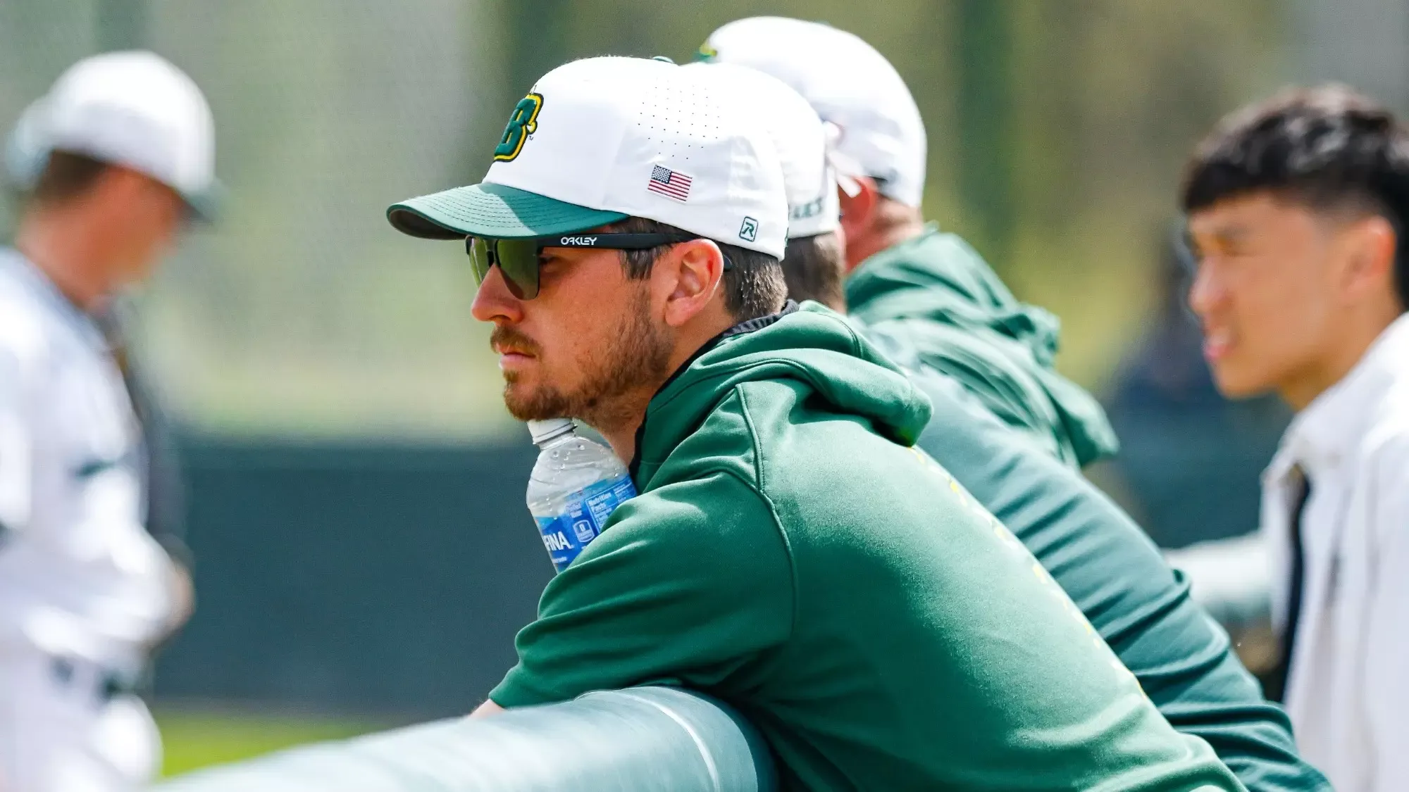 New Cornell baseball assistant coach Kyle Canavally stands in SUNY Brockport's dugout during game action.