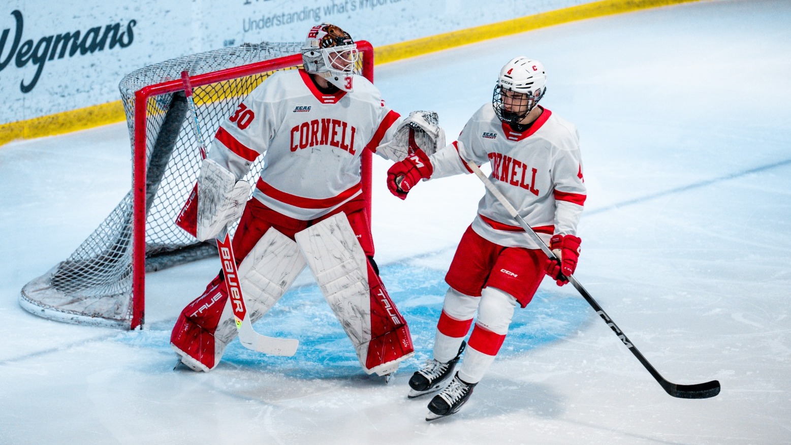 Cornell men's hockey freshman goaltender Alexis Cournoyer and freshman defenseman Xavier Veilleux fist bump during game action against Harvard on March 15, 2025.