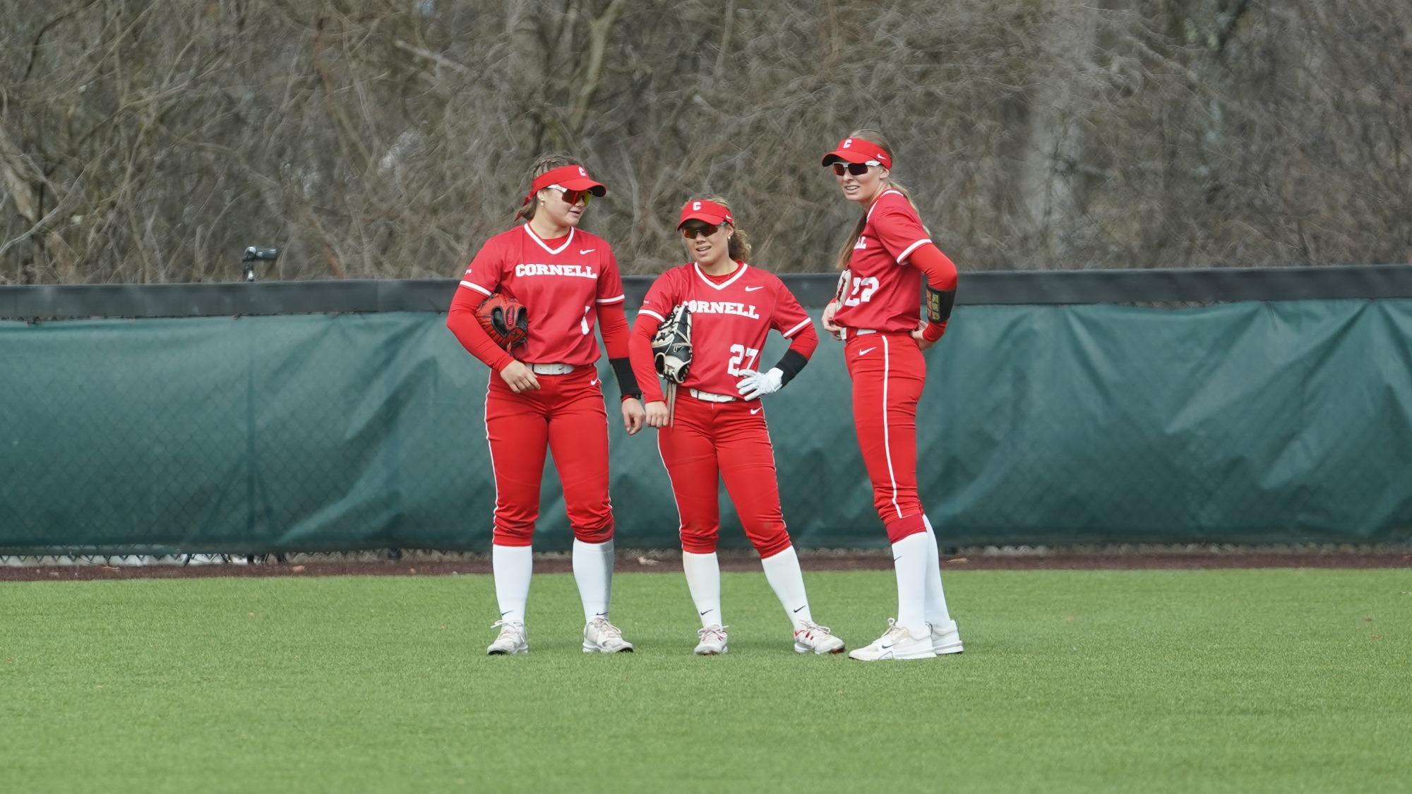 Cornell softball players huddle in the outfield at Niemand-Robison Field.