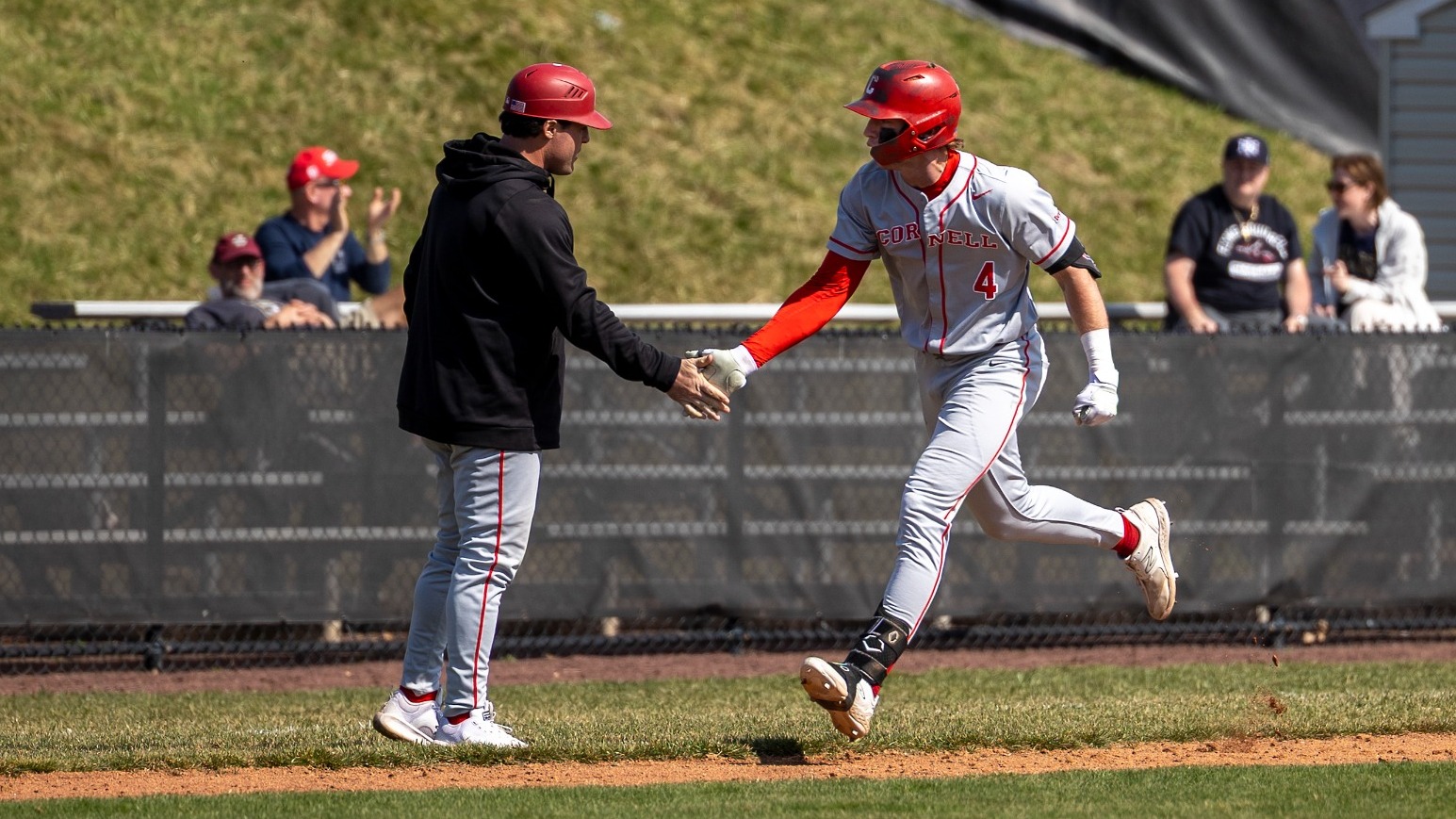 Cornell baseball senior outfielder Caden Wildman high-fives third-base coach John Toppa after hitting a home run against Princeton on March 22, 2026, at Clarke Field in Princeton, N.J.