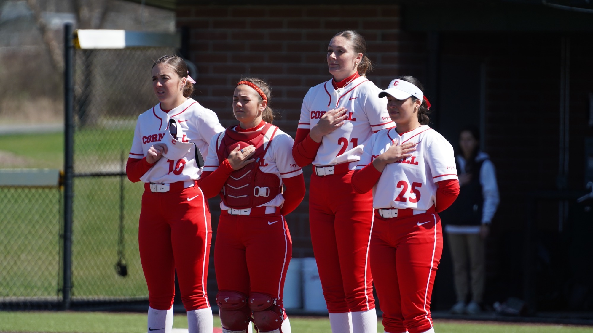 Softball players stand for the national anthem at Niemand-Robison Field.