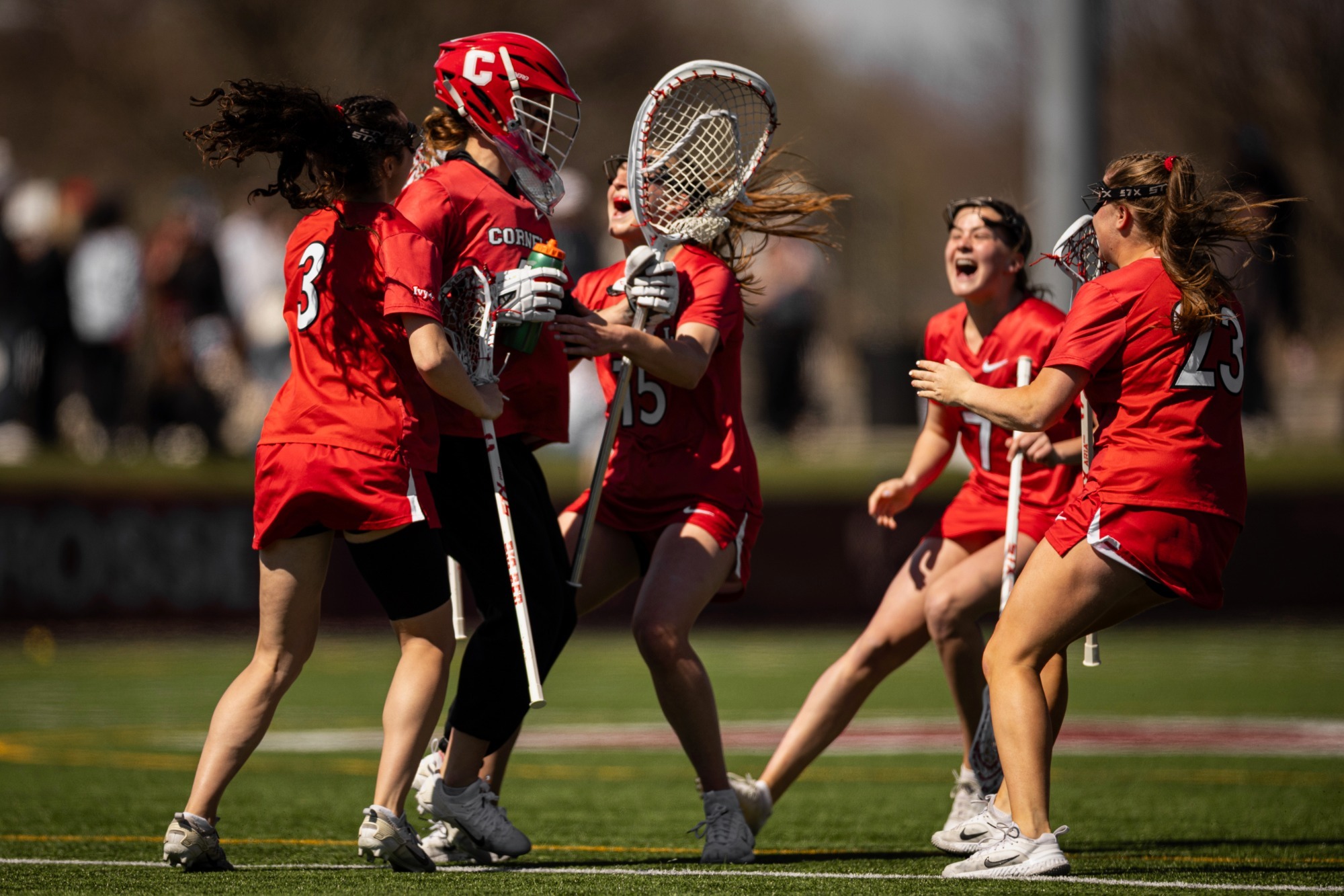 Cornell women's lacrosse celebrates on Jordan Field after beating Harvard, 13-11