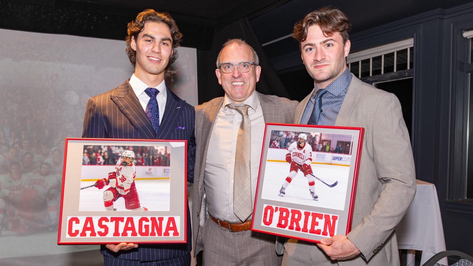 Cornell men's hockey junior forward Jonathan Castagna and senior defenseman Jack O'Brien pose with head coach Casey Jones '90 with plaques after the 63rd annual CHA Men's Hockey Banquet at RaNic Golf Club in Ithaca, N.Y., on April 17, 2026.