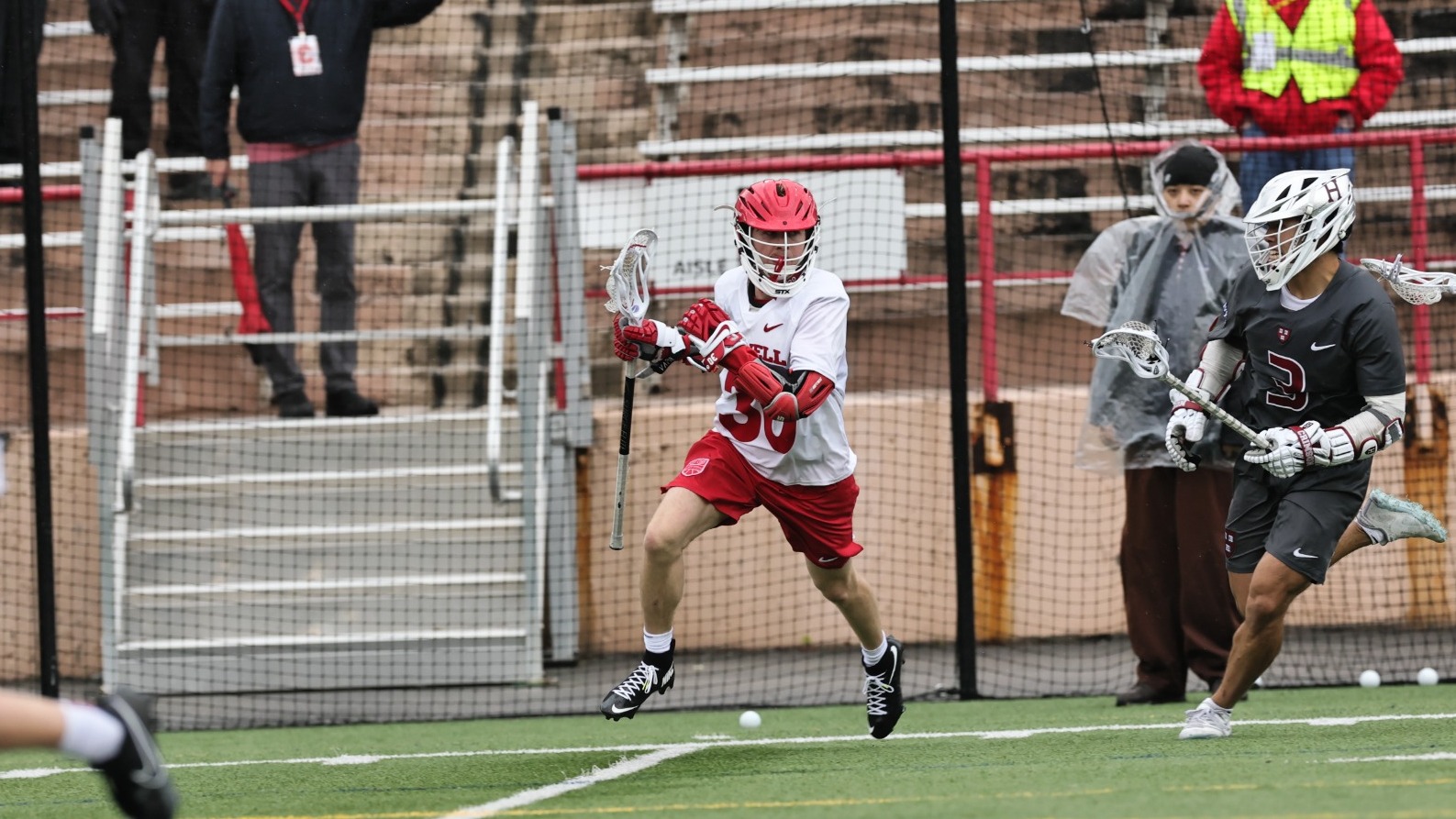 Cornell men's lacrosse attackman Ryan Goldstein (#30) drives toward the cage during a home game at Schoellkopf Field, with a Harvard defender giving chase.