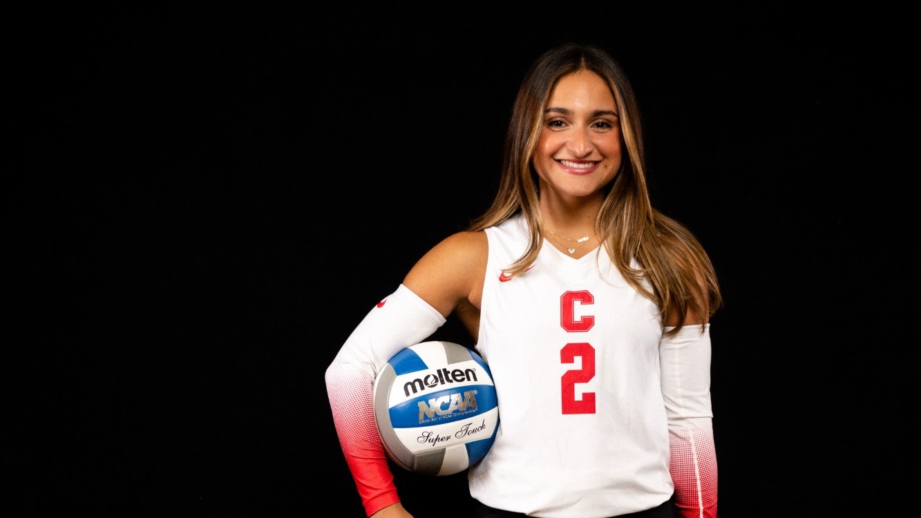 Sara Pomar of women's volleyball posing for media day 2026 with black back drop and volleyball under her right arm