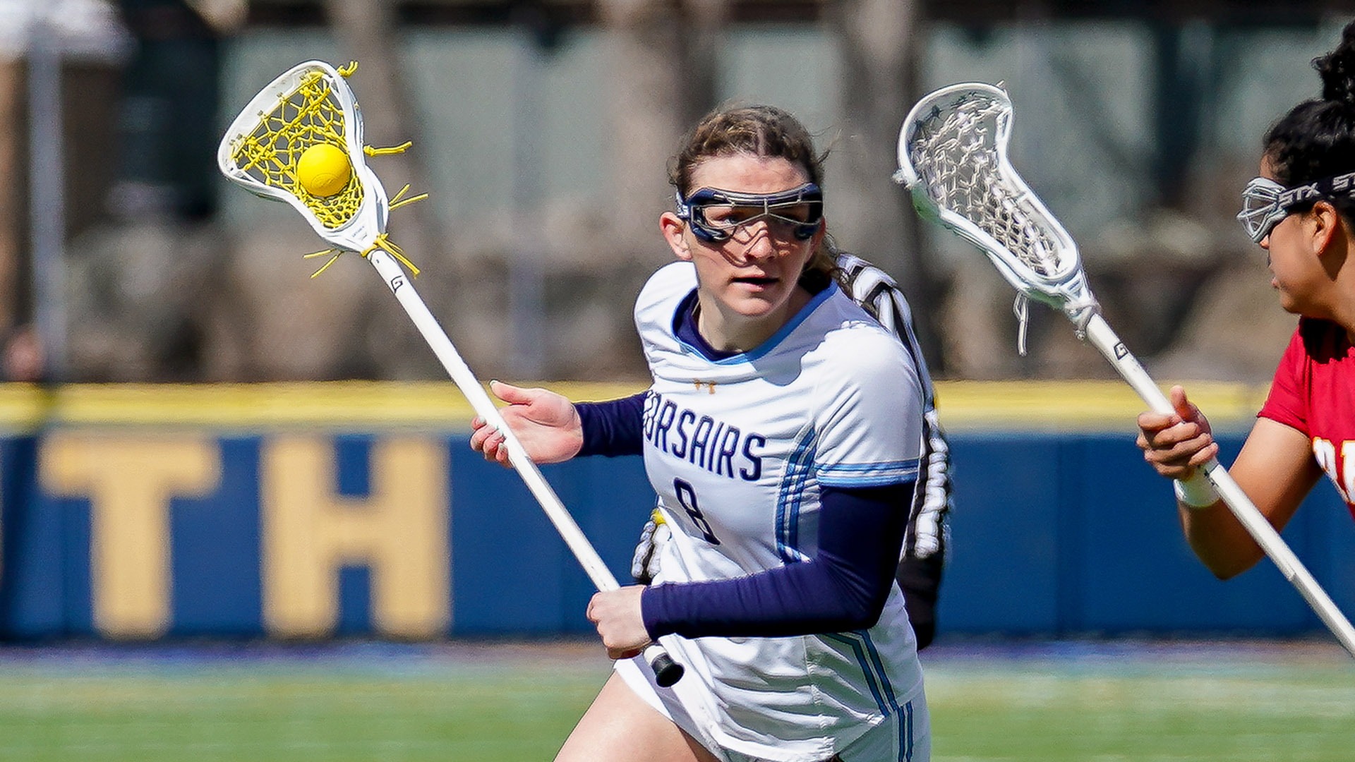 Maddy Allen carries the ball in a women's lacrosse game versus Regis College - March 2026