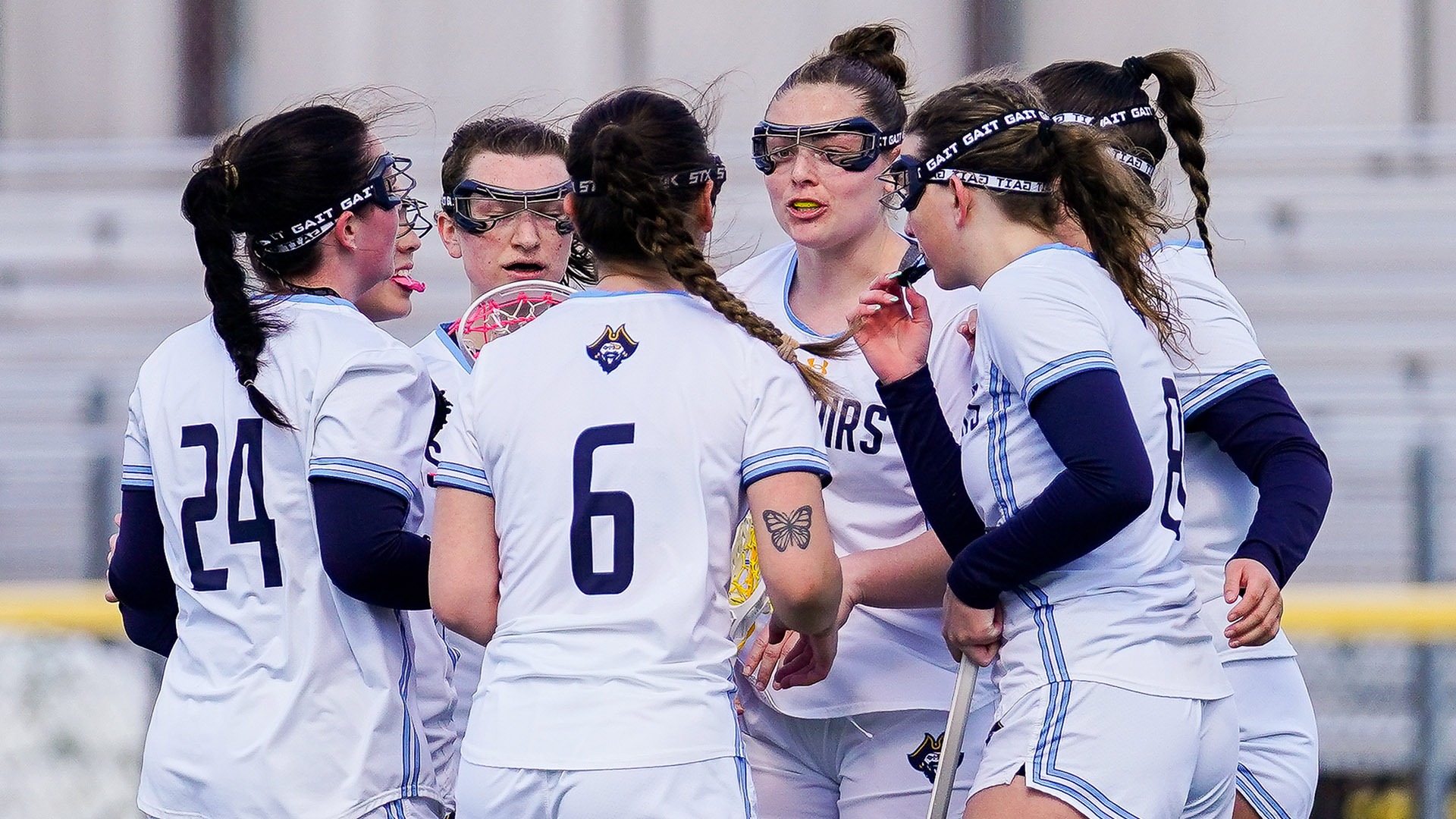 Members of the women's lacrosse team huddle after a goal