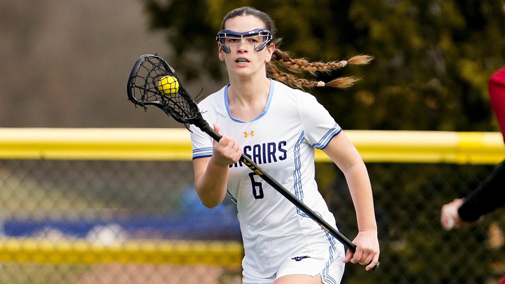 Katie Hague carries the ball in a women's lacrosse game against Regis - March 2026