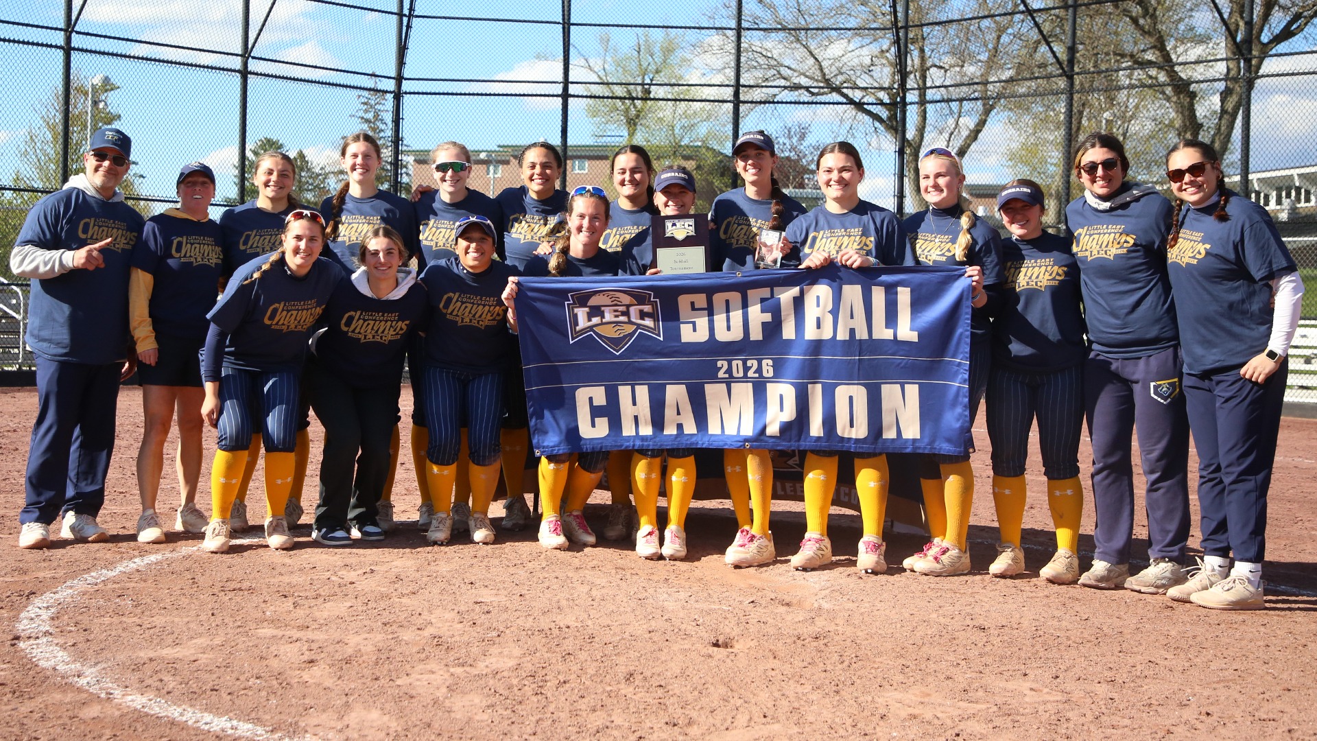 UMass Dartmouth softball poses with the banner and trophy to celebrate winning 2026 Little East Championship