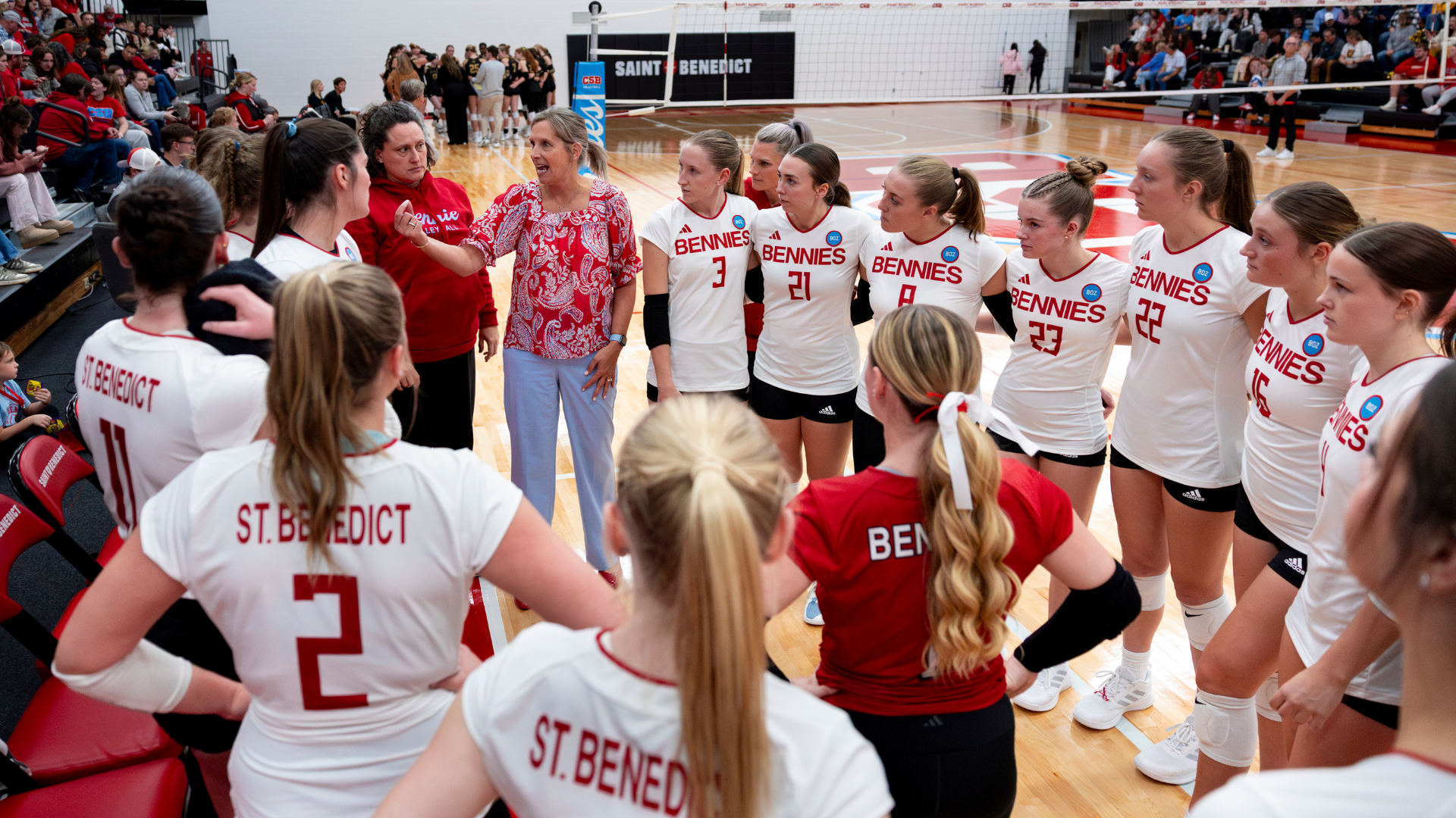 Volleyball team huddles while head coach Nicole Hess talks
