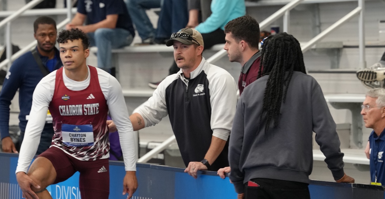 Head Coach Jake Gruver with assistant coach Creighton Trembly and student-athlete Chayton Bynes conversing at the NCAA National Indoor Track and Field Championships.