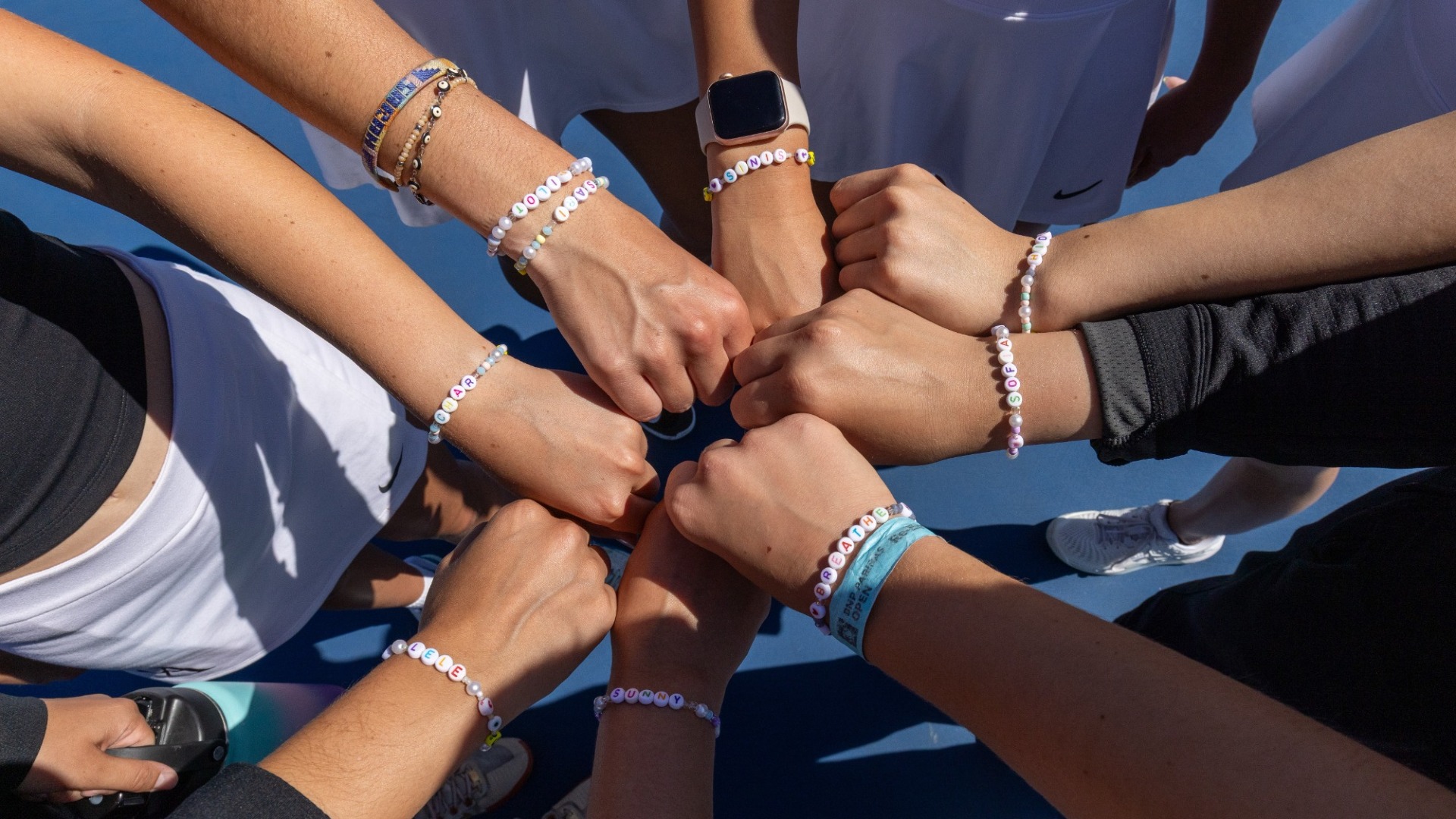 tennis team puts hands together before a match