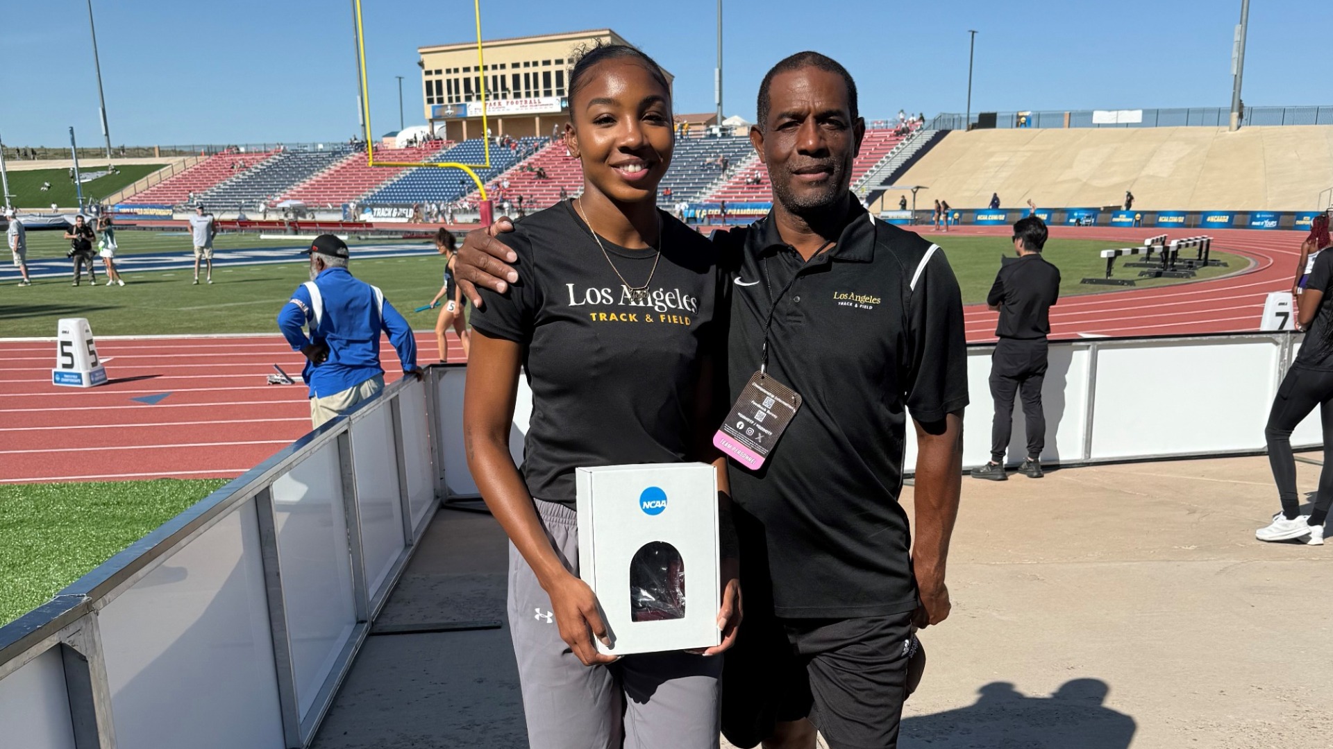 jonon young and assistant coach sean fernandez pose with ncaa long jump award