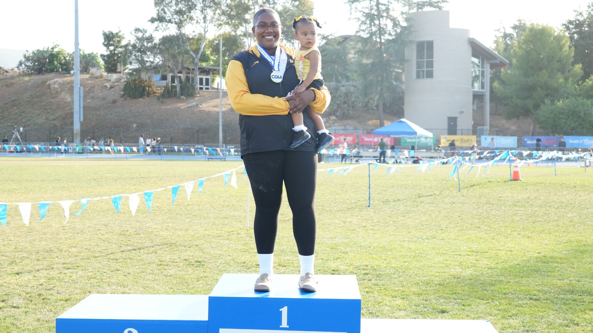 kailea satterwhite stands atop the podium after winning ccaa discus championship