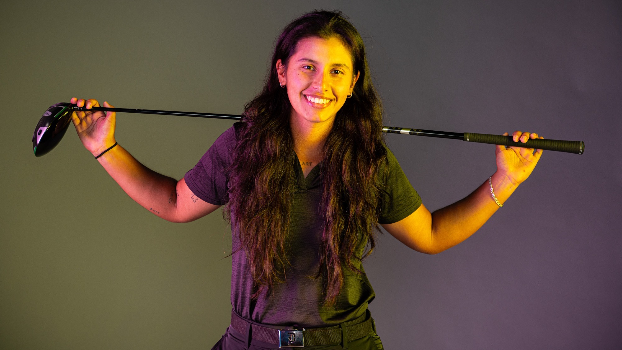 daniela andrade poses with a golf club on media day