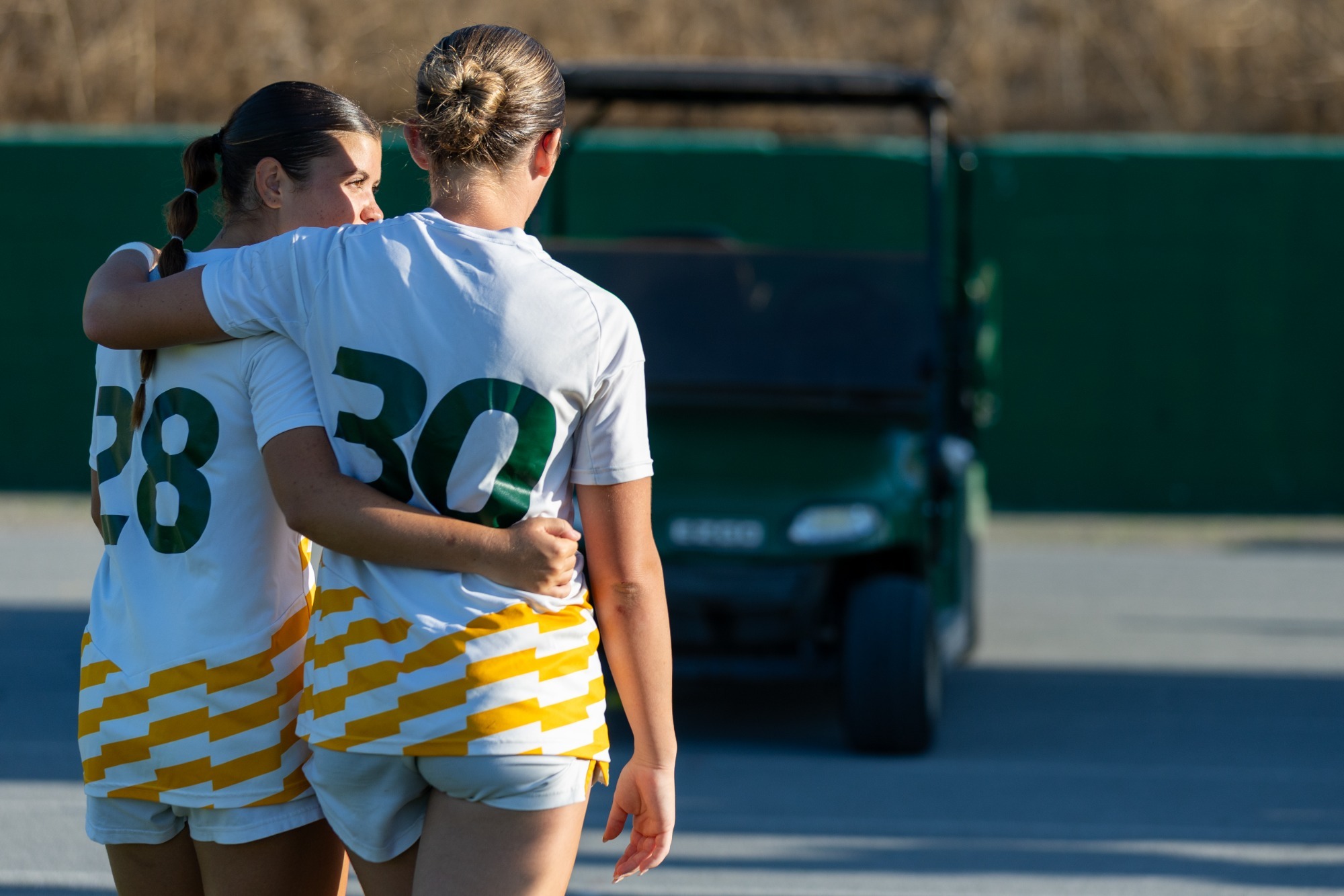 Madison Hall and Bella Barrett hugging walking off home field
