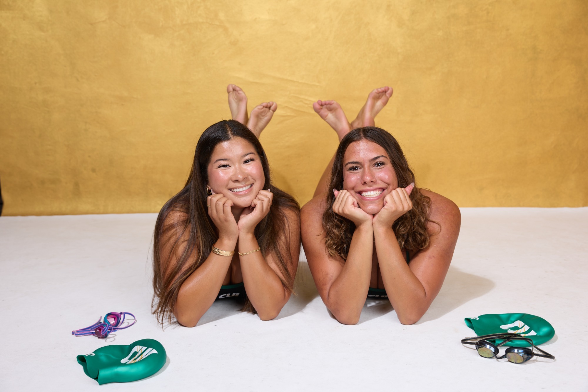 Alexandra Grant and Carissa Ward smiling lying down with goggles and caps