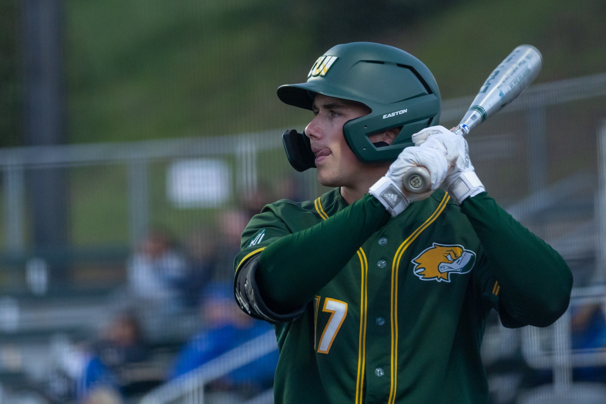 Wyatt Madison licking his chops during junior season at-bat in green CUI jersey