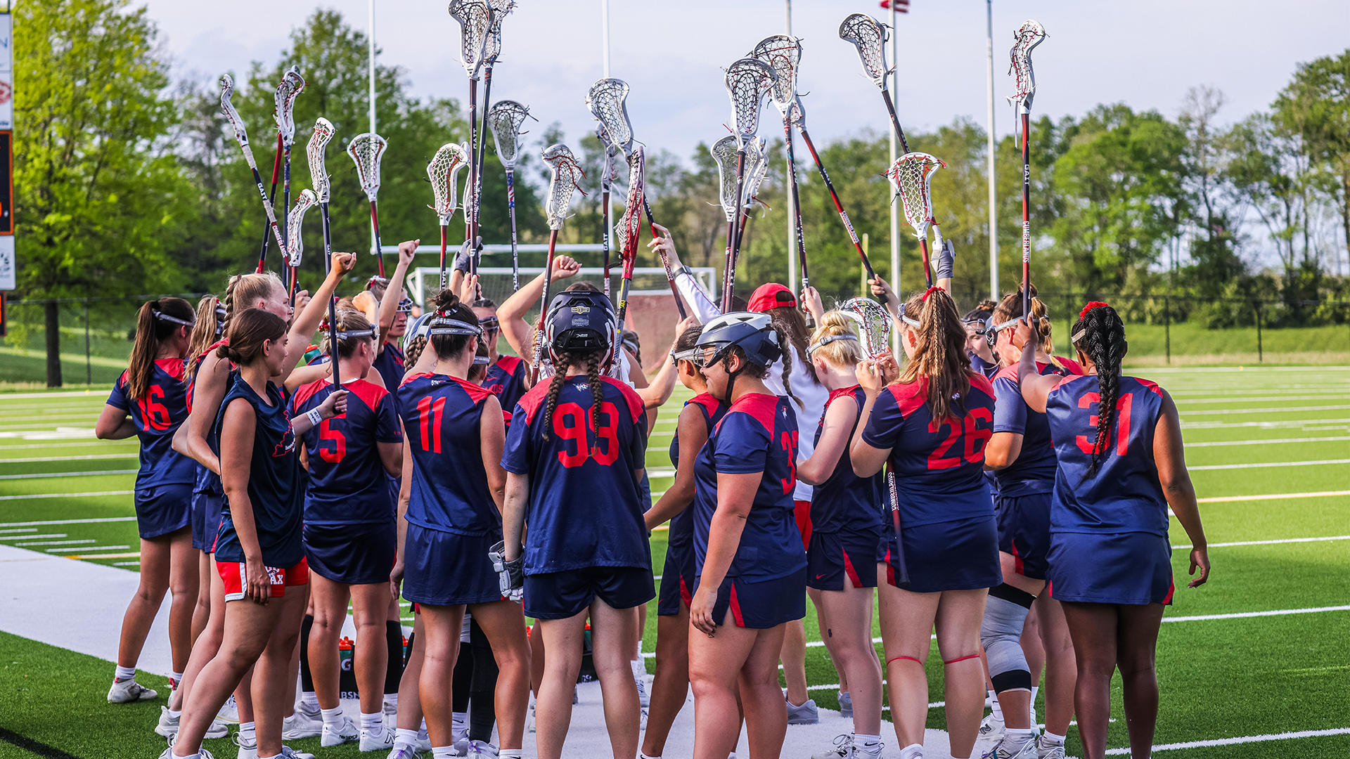 Patriots WLAX Team Huddle with sticks in the air