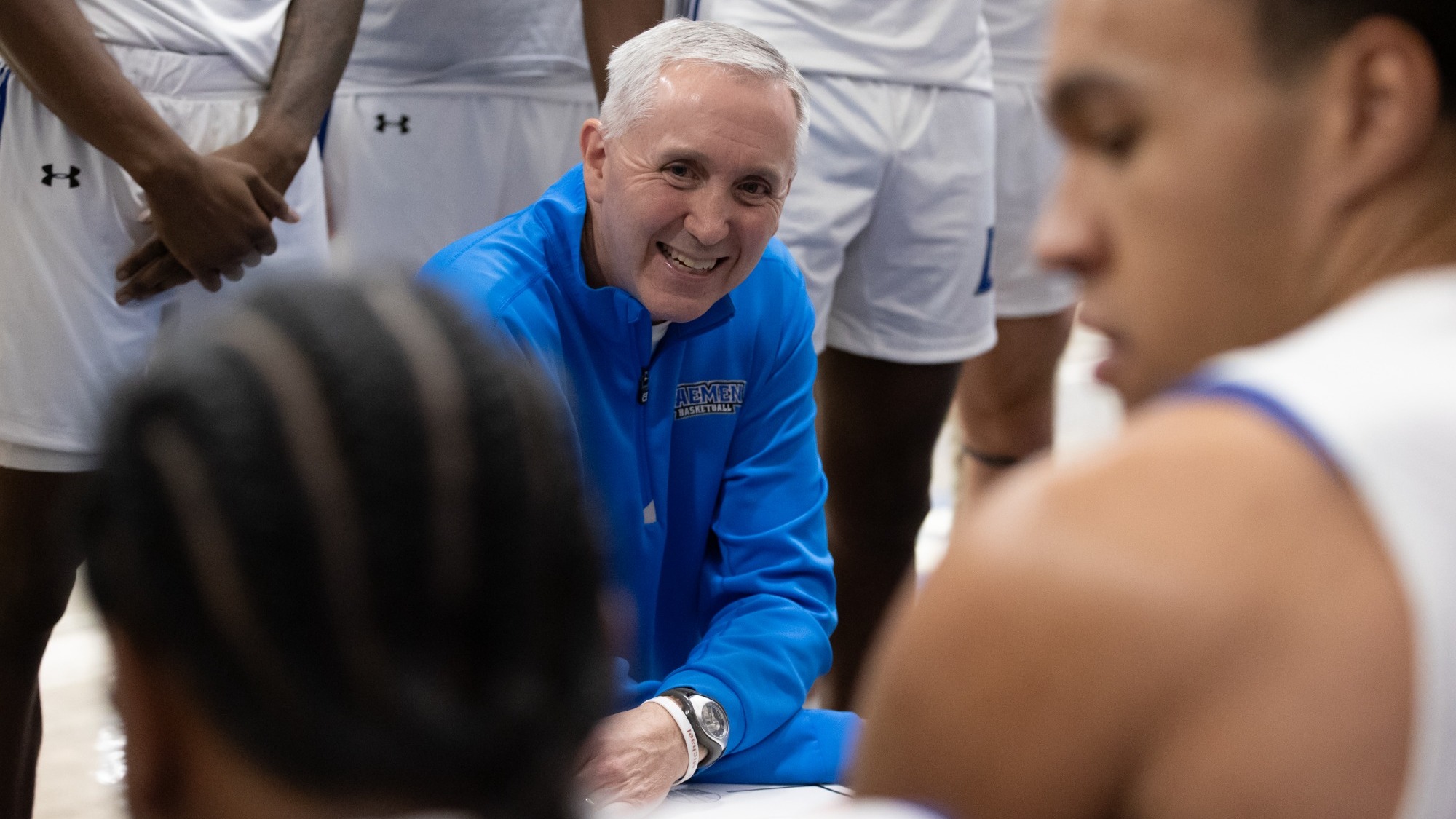 Mike MacDonald smiles in a team huddle during a timeout