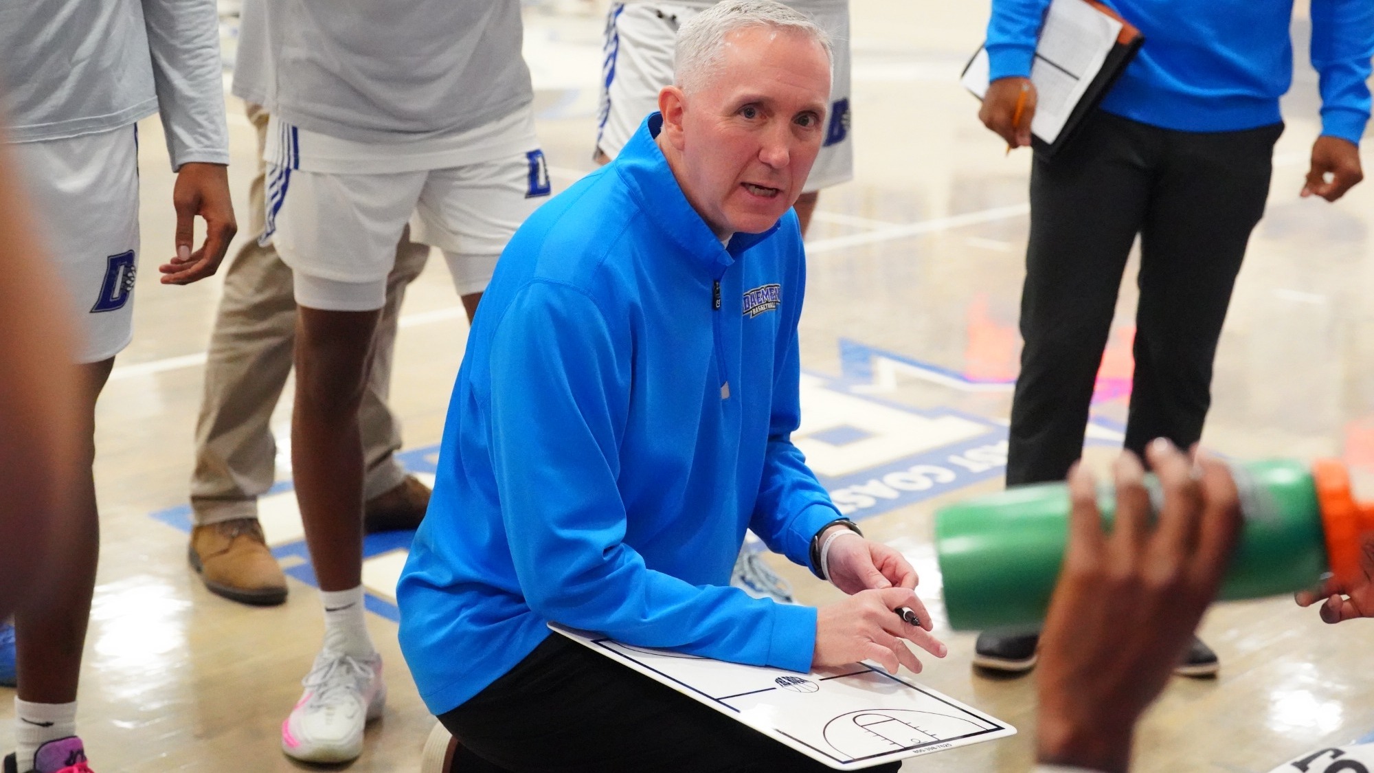 Mike MacDonald addresses the Daemen men's basketball team during a timeout
