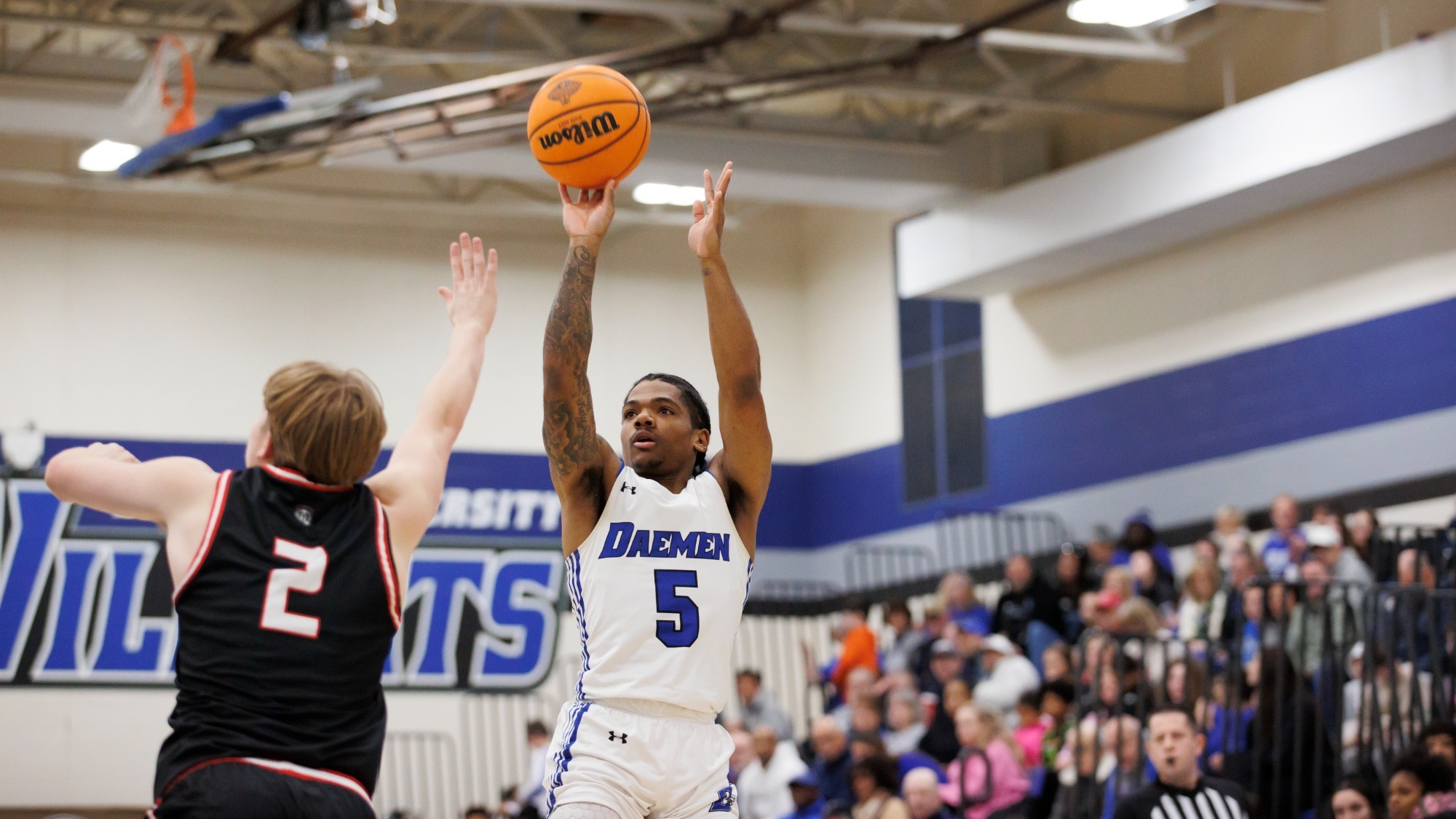 Justin Glover shoots as the Daemen crowd looks on
