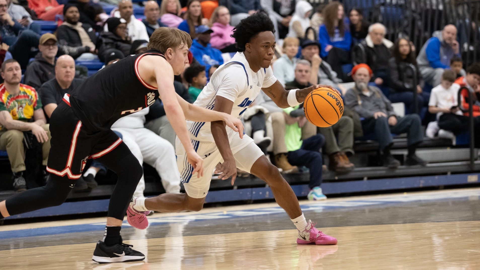 Nakyhi Harris dribbles while a D'Youville defender tries to stay in front of him as the Lumsden Gymnasium crowd looks on