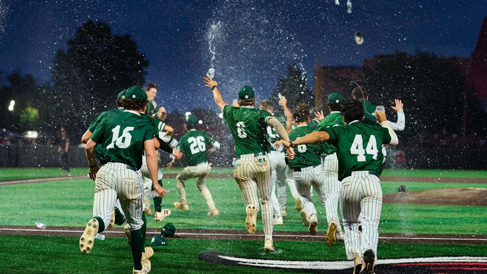 baseball team celebrates with water flying in the air after win