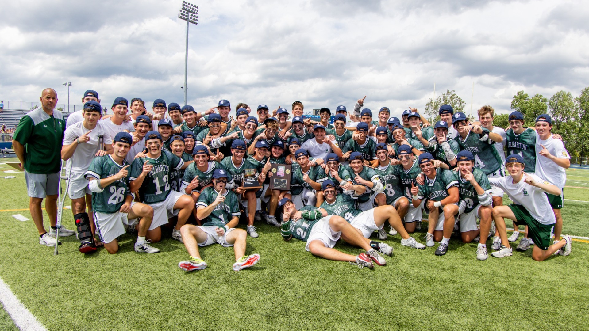 team celebrates for photo on the field with kirst cup trophy after winning title.