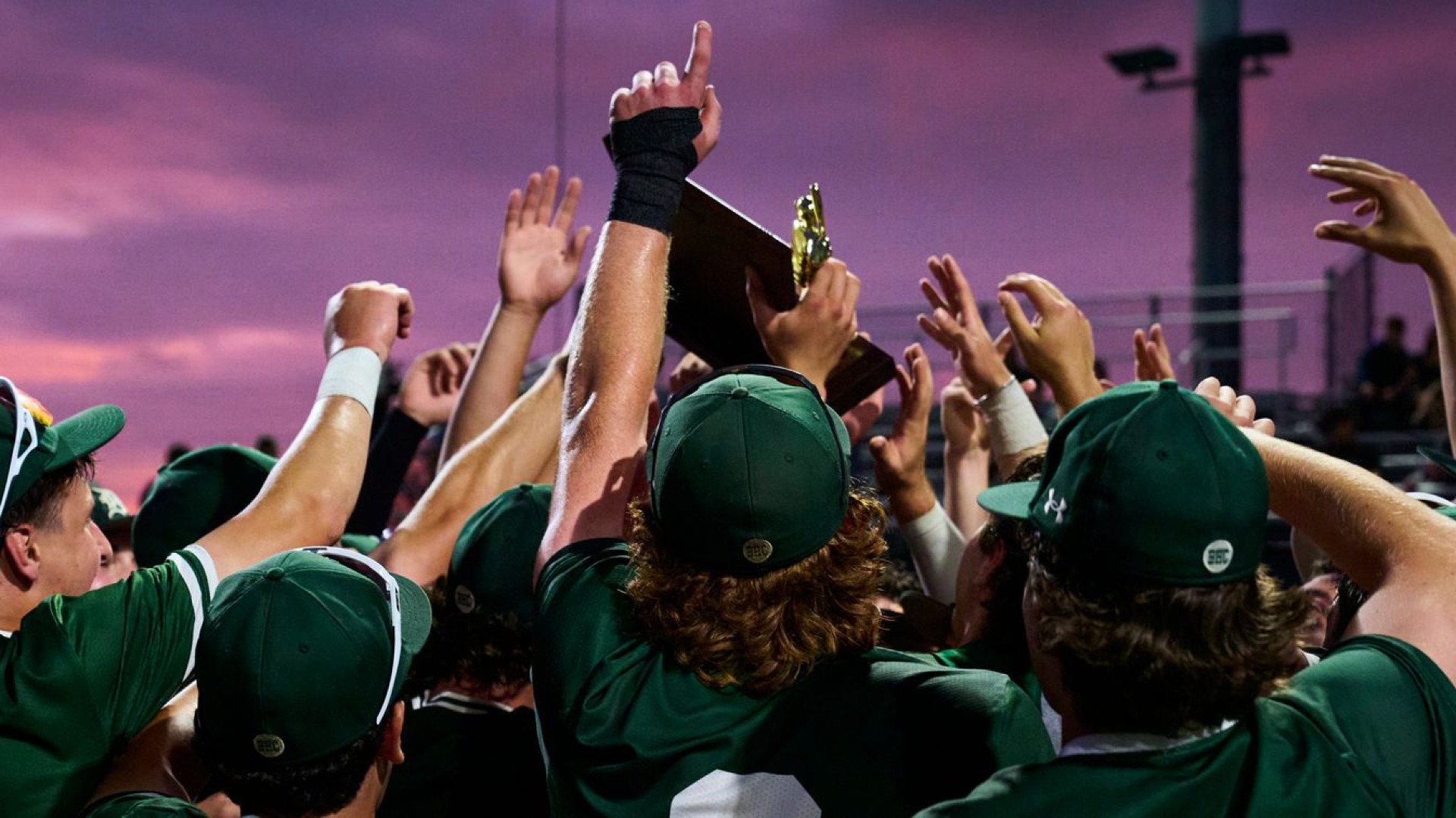 team huddle celebrates with trophy in the air after winning state title