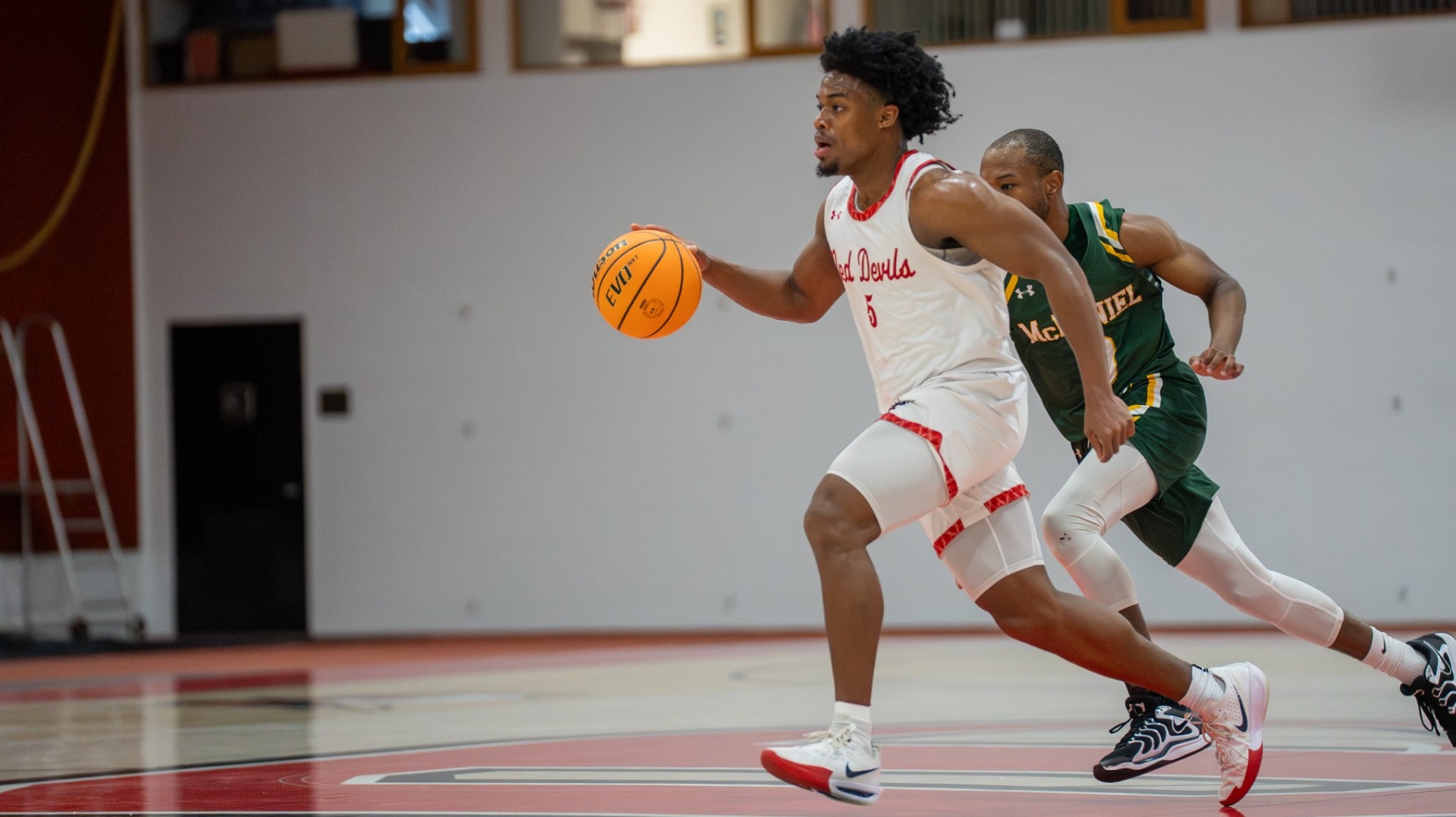 Isaiah Edmond dribbling away from a McDaniel College defender on 2-15-25
