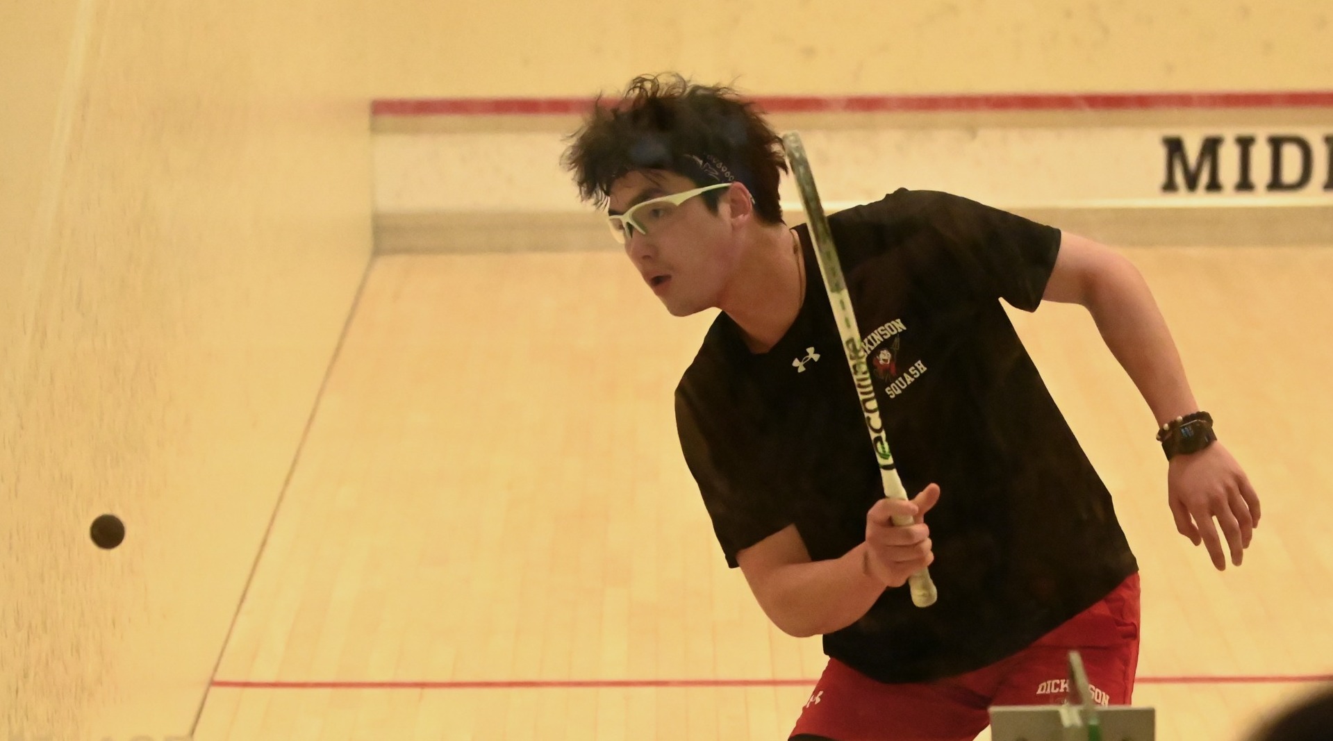 Men's squash player going for a backhand shot at Middlebury College during the 2026 New England trip.